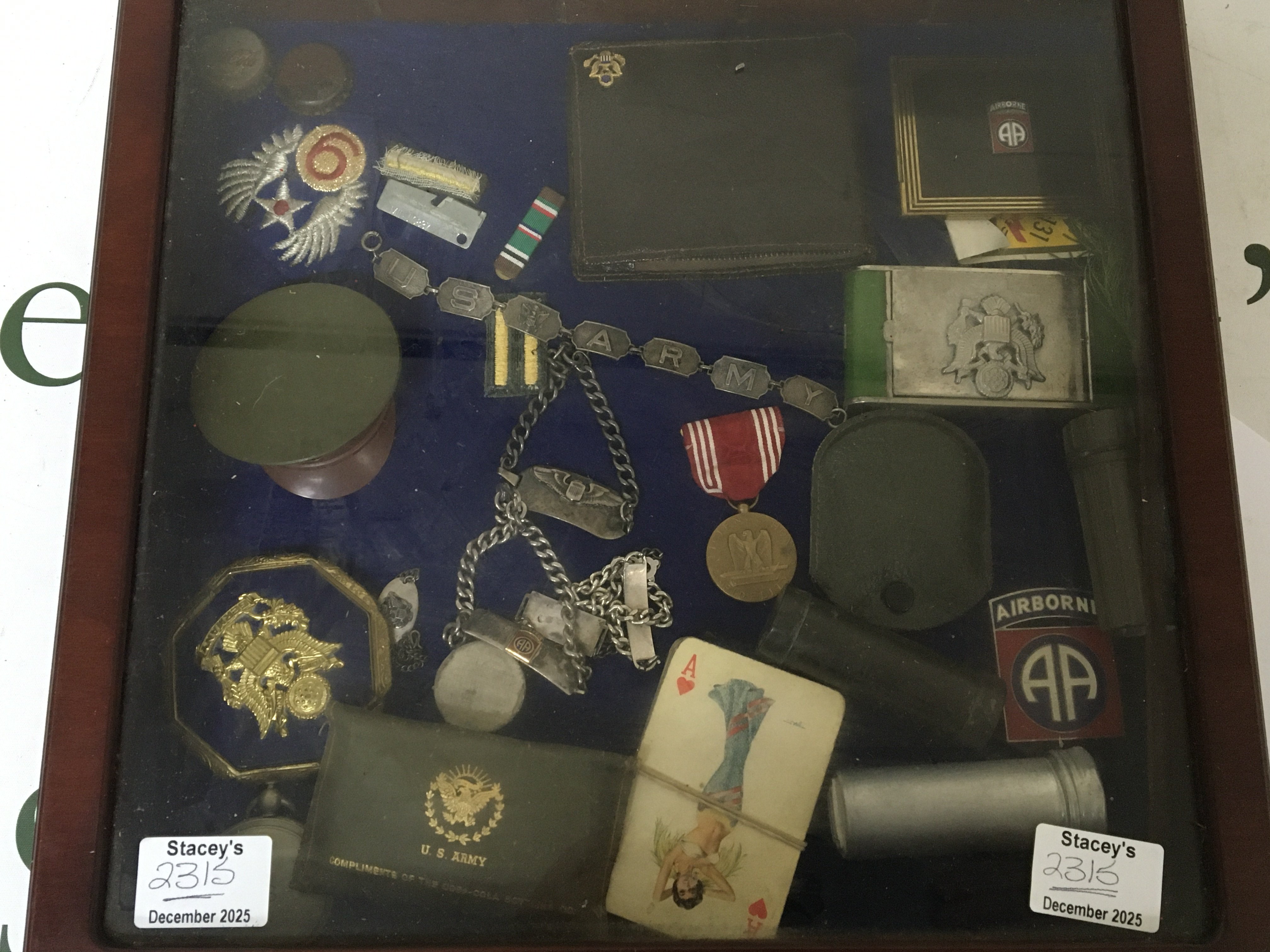A Case containing American Airborne enamel badges ID bracelet a white metal US Army bracelet. And other associated items.