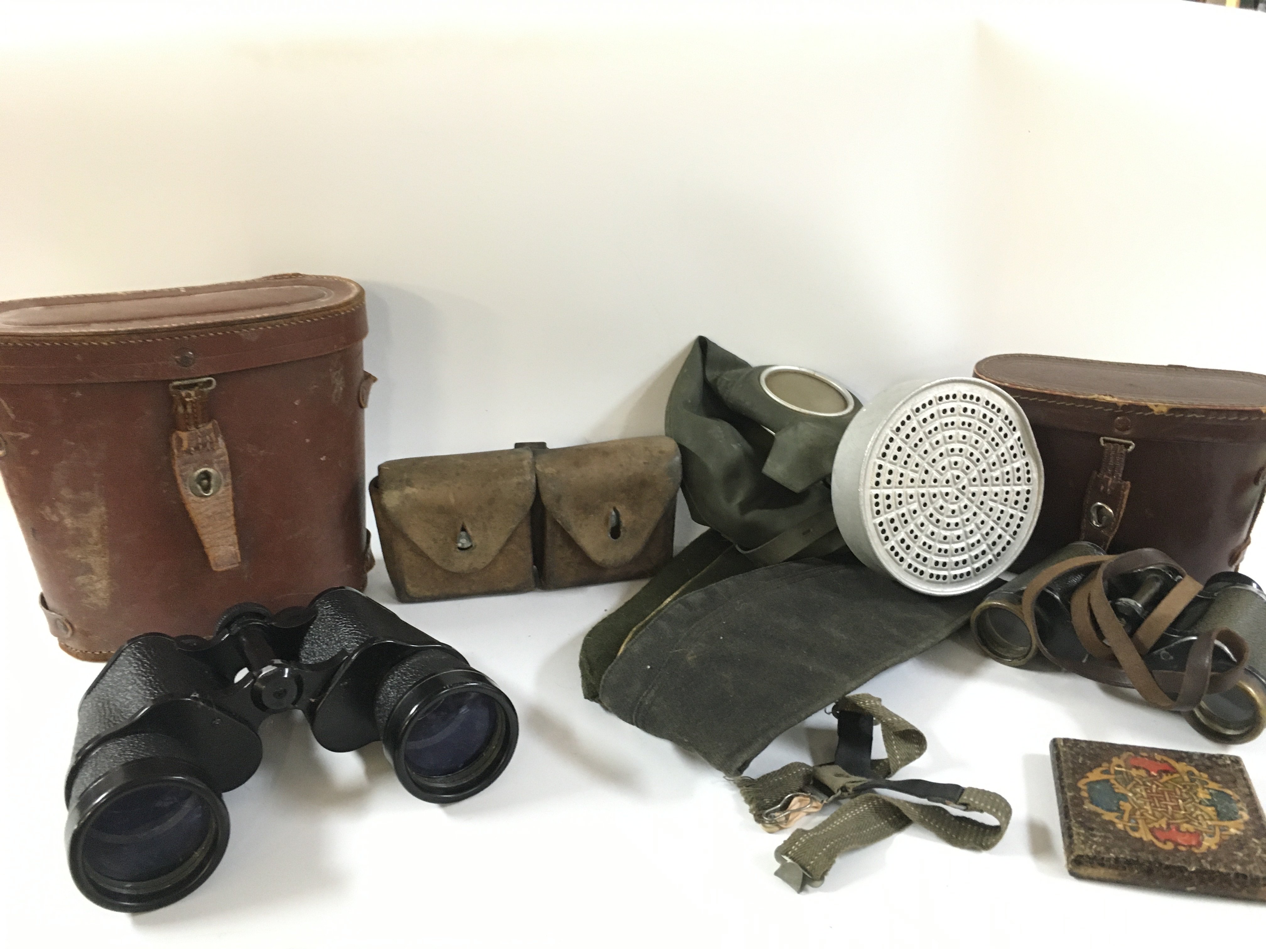 A collection of various military items including a gas mask, binoculars , leather ammo pouch, side caps etc. this lot cannot be posted