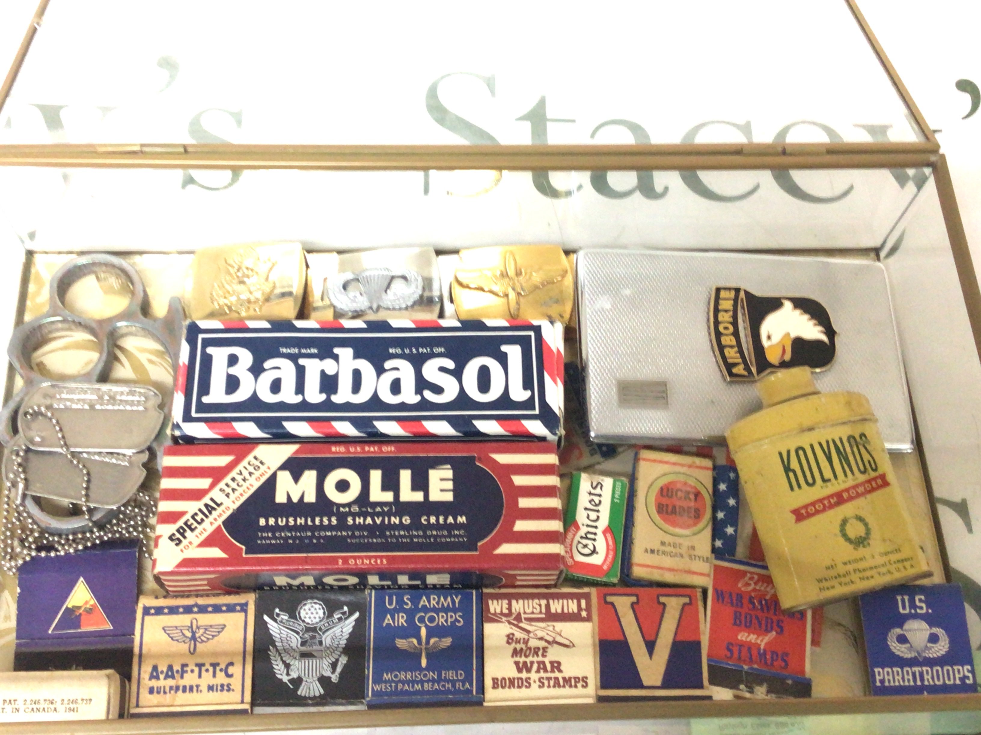 A display case containing II world war American military related items books of matches Airborne cigarette case and other items.