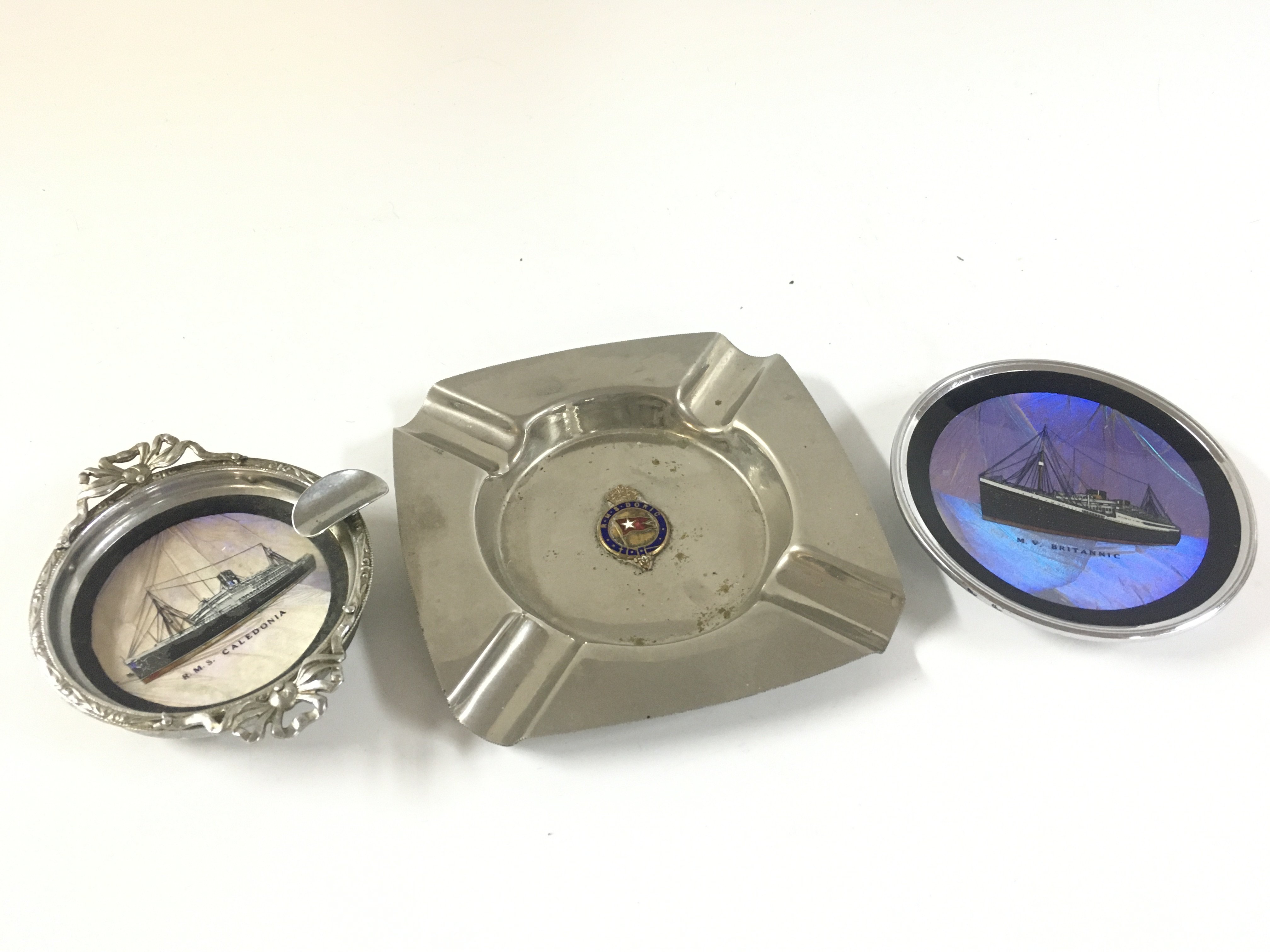 Three extremely rare maritime artefacts - a Very rare find souvenir dish from the white star line vessel The Britannic, very rare silver plated ashtray from the white star line RMS Doric circa 1930s, embossed chrome ashtray from the liner RMS Caledonia