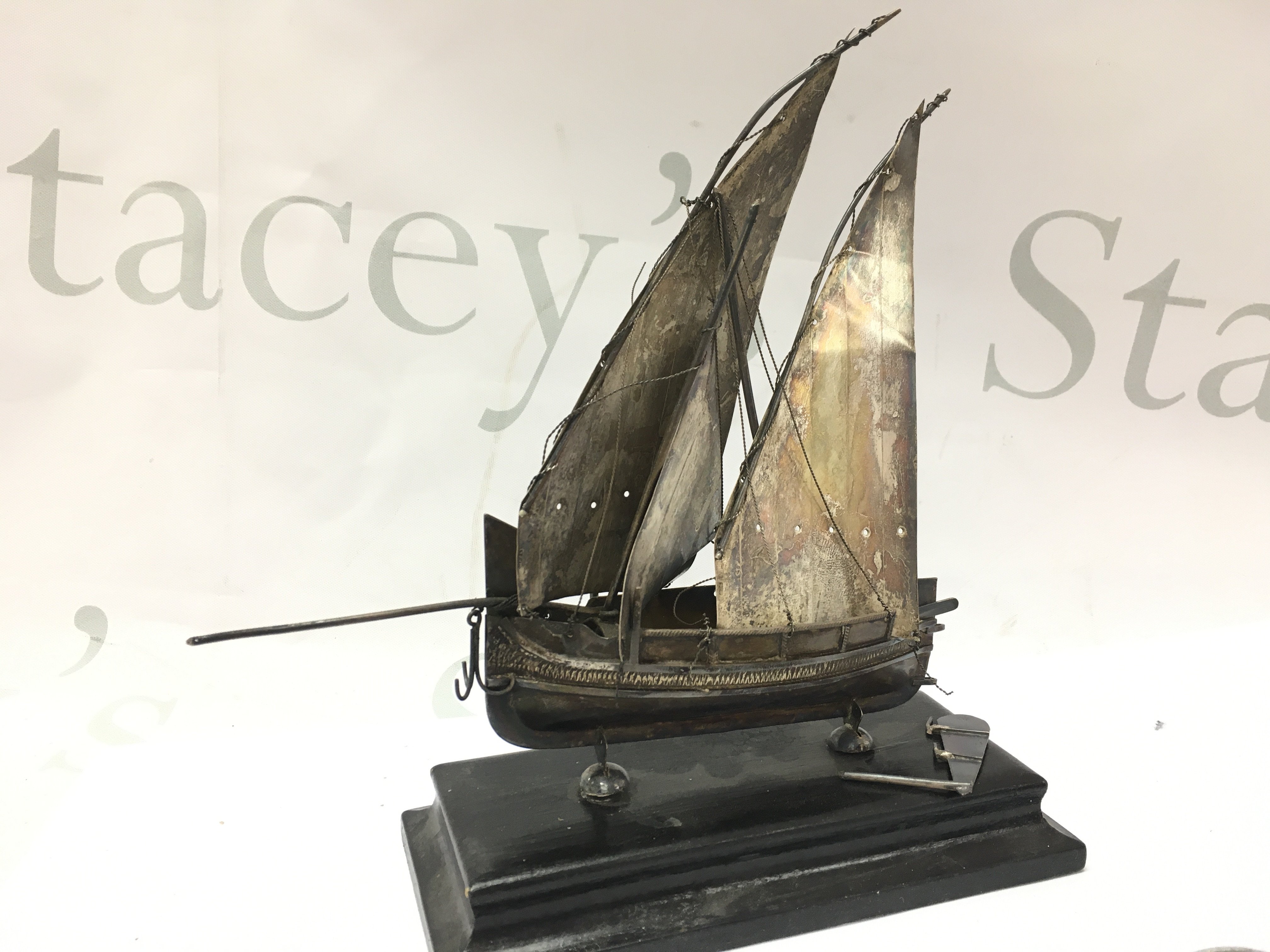 A hallmarked silver model boat (approximately 19.5cm tall including stand). In need of restoration Postage category B