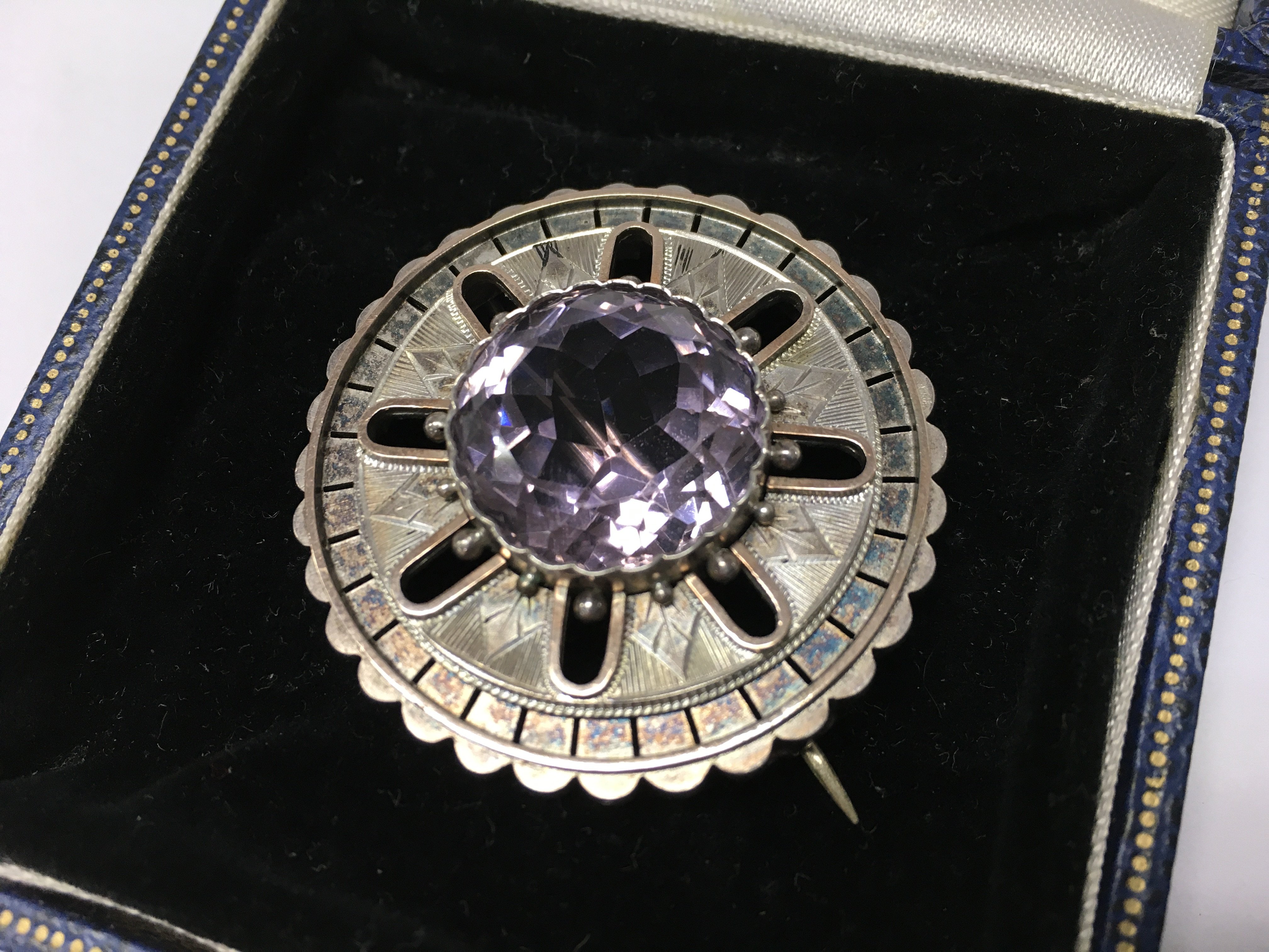 A silver brooch with a large central amethyst
