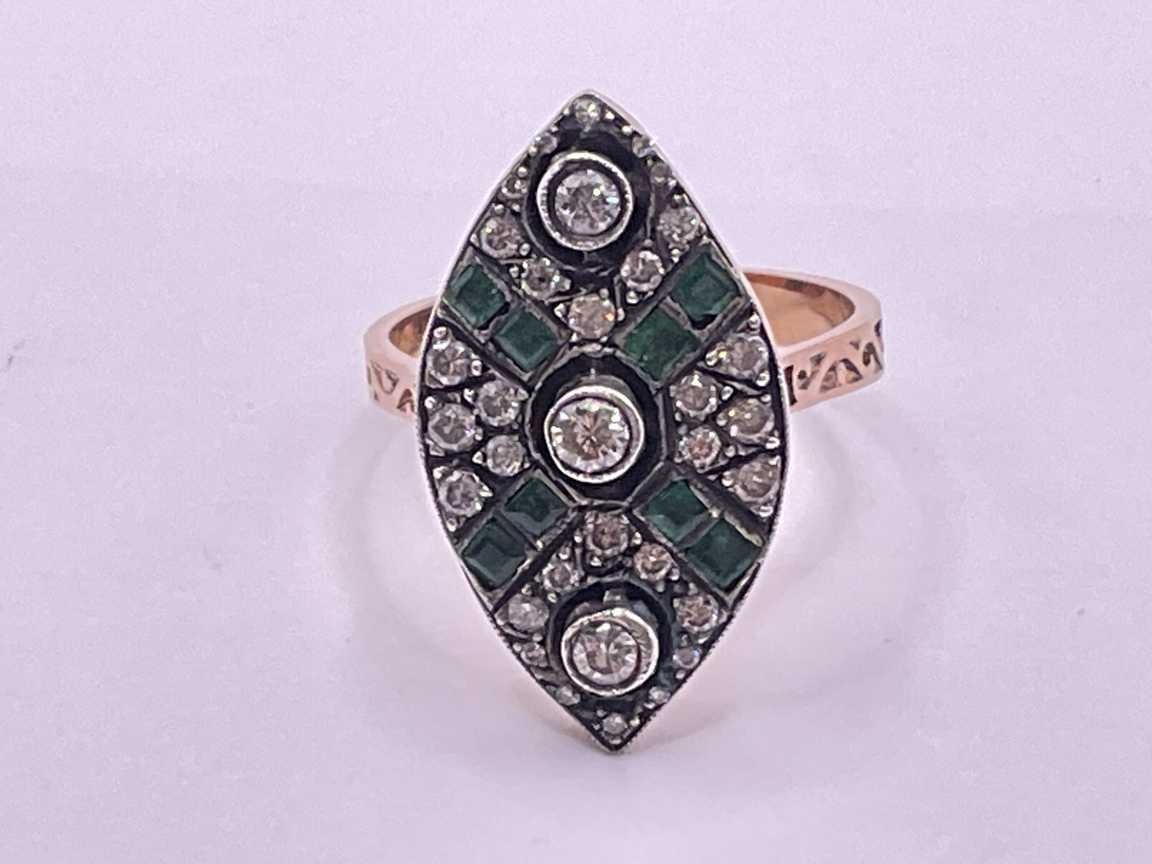 Unhallmarked rose gold and silver topped navette shaped shaped ring set with RBC diamonds and square step cut emeralds. Diamonds 0.60ct approx. Emeralds 0.20ct approx. Ring size approx N/O. Postage category A.