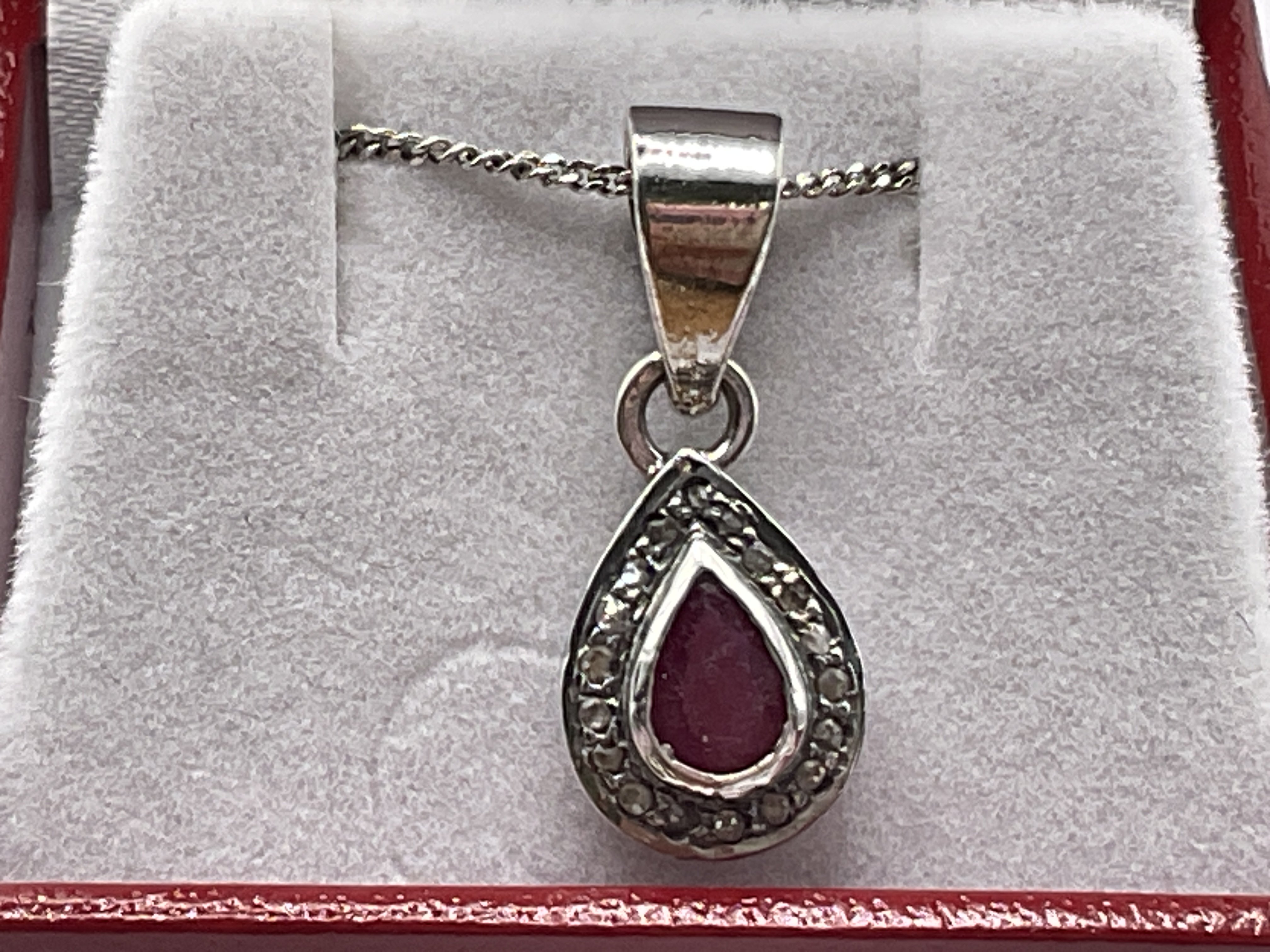 Silver pear shaped pendant set with pear shaped ruby and a halo of R/C diamonds, boxed. Ruby 0.28ct approx. Diamonds 0.51ct approx. Postage category A.