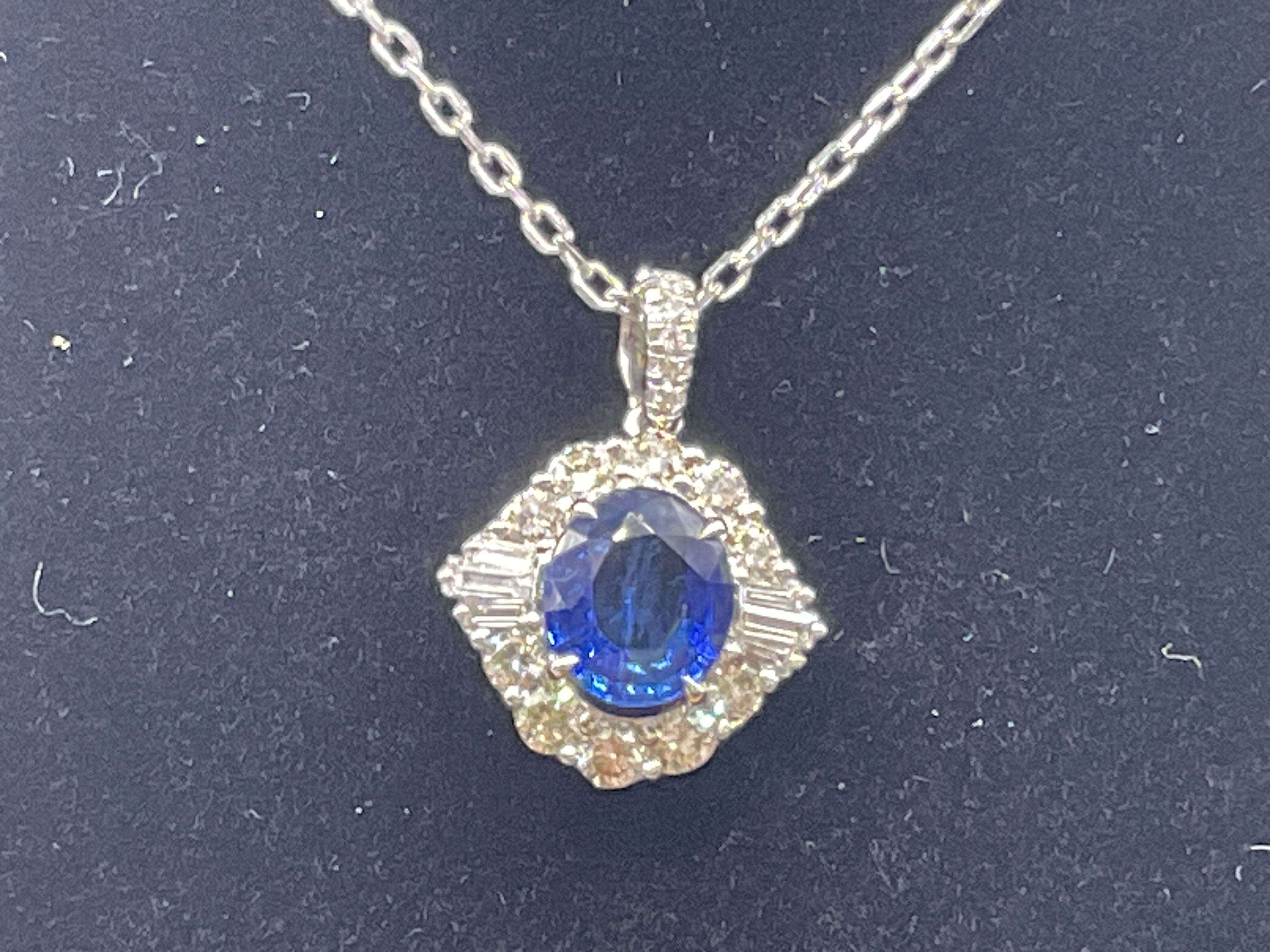 18ct white gold oval sapphire and diamond cluster necklace, on an 18ct white gold chain, boxed. Sapphire 1.42ct. RBC and baguette cut diamonds 0.63ct. Postage category A.