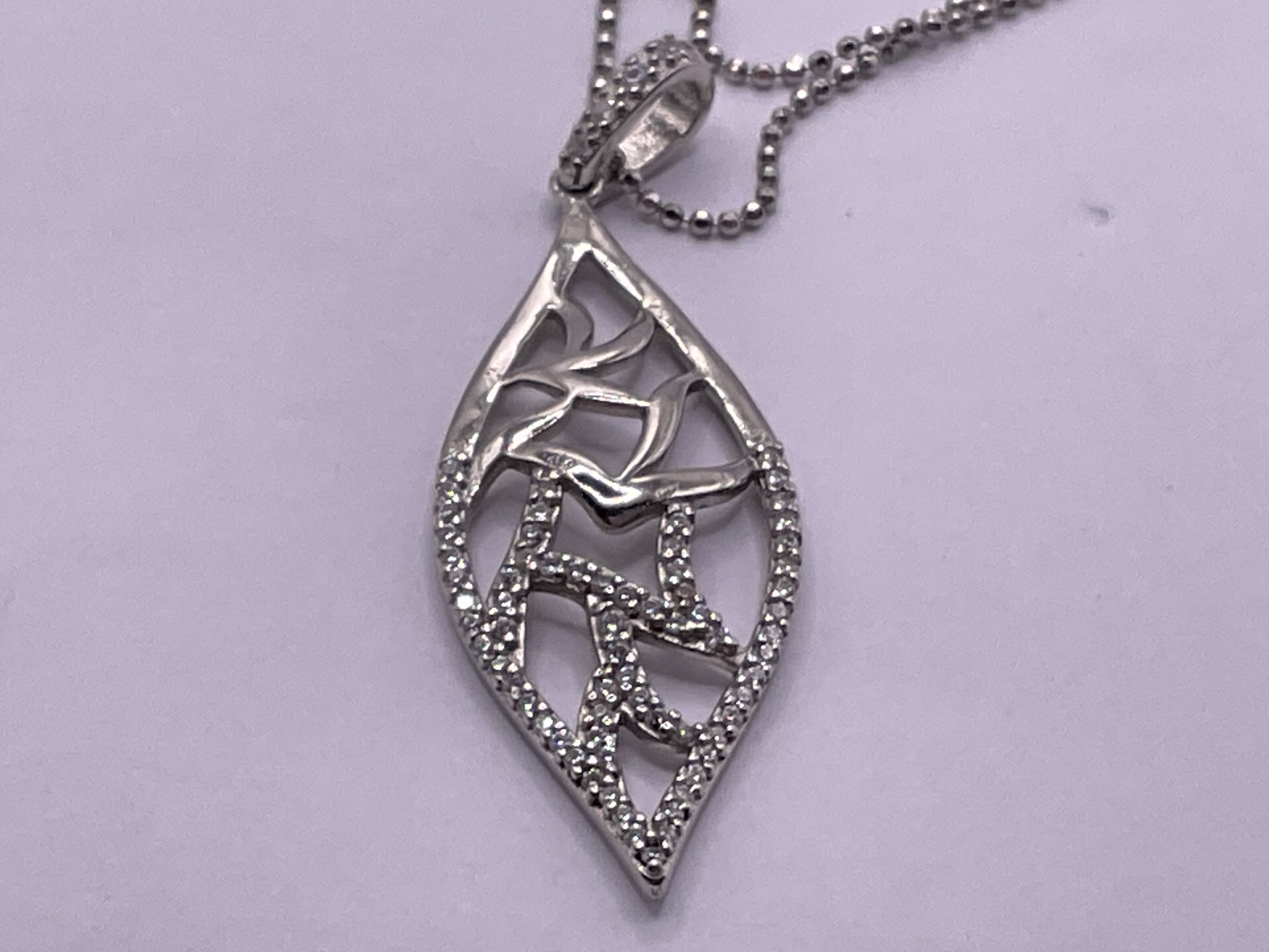 Silver necklace comprising an open work leaf shaped pendant set with cubic zirconia, with a silver chain. Postage category A.