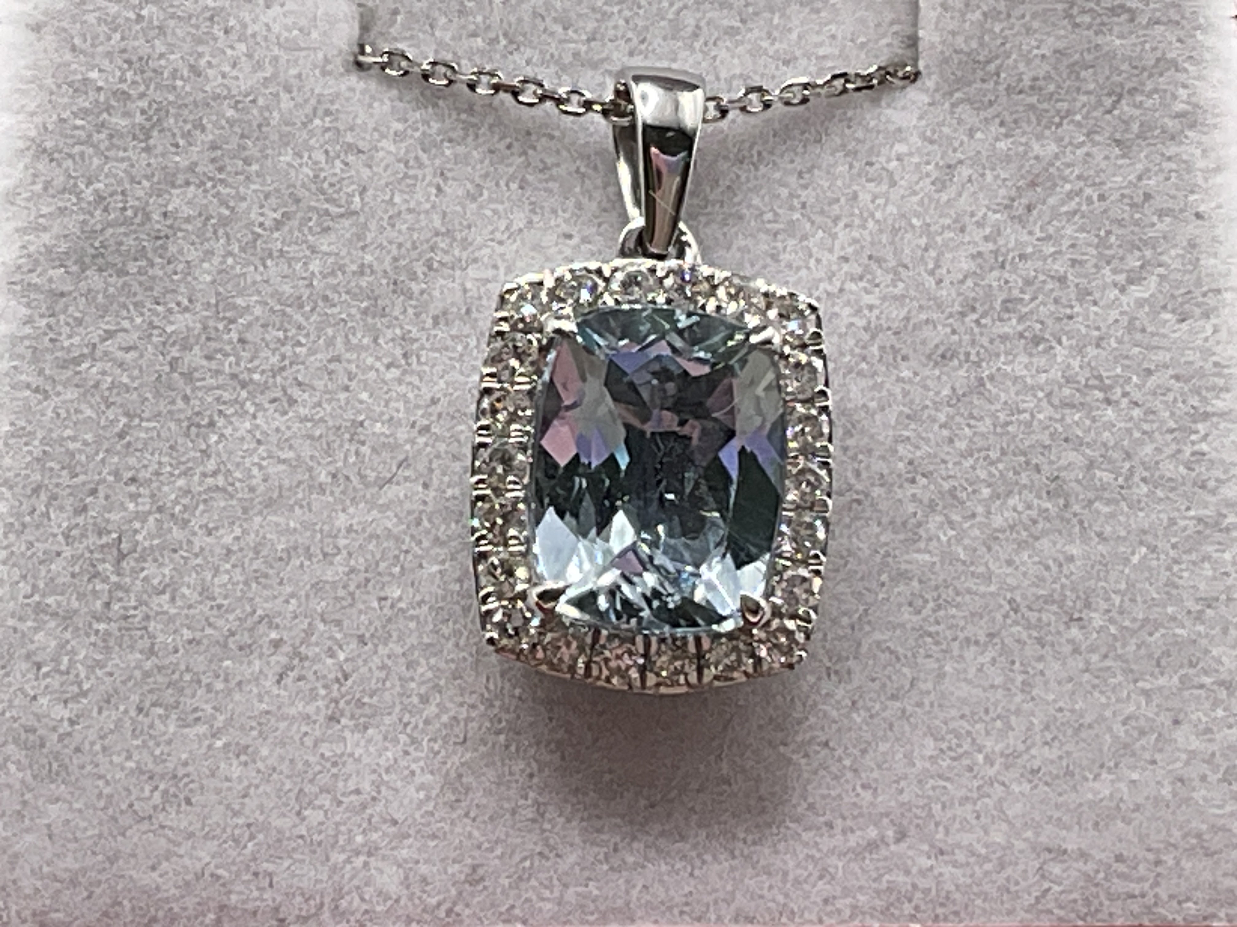9ct white gold cushion cut aquamarine and RBC diamond cluster pendant on a 9ct white gold chain, boxed. Aquamarine 1.92ct. Diamonds 0.26ct. Postage category A.