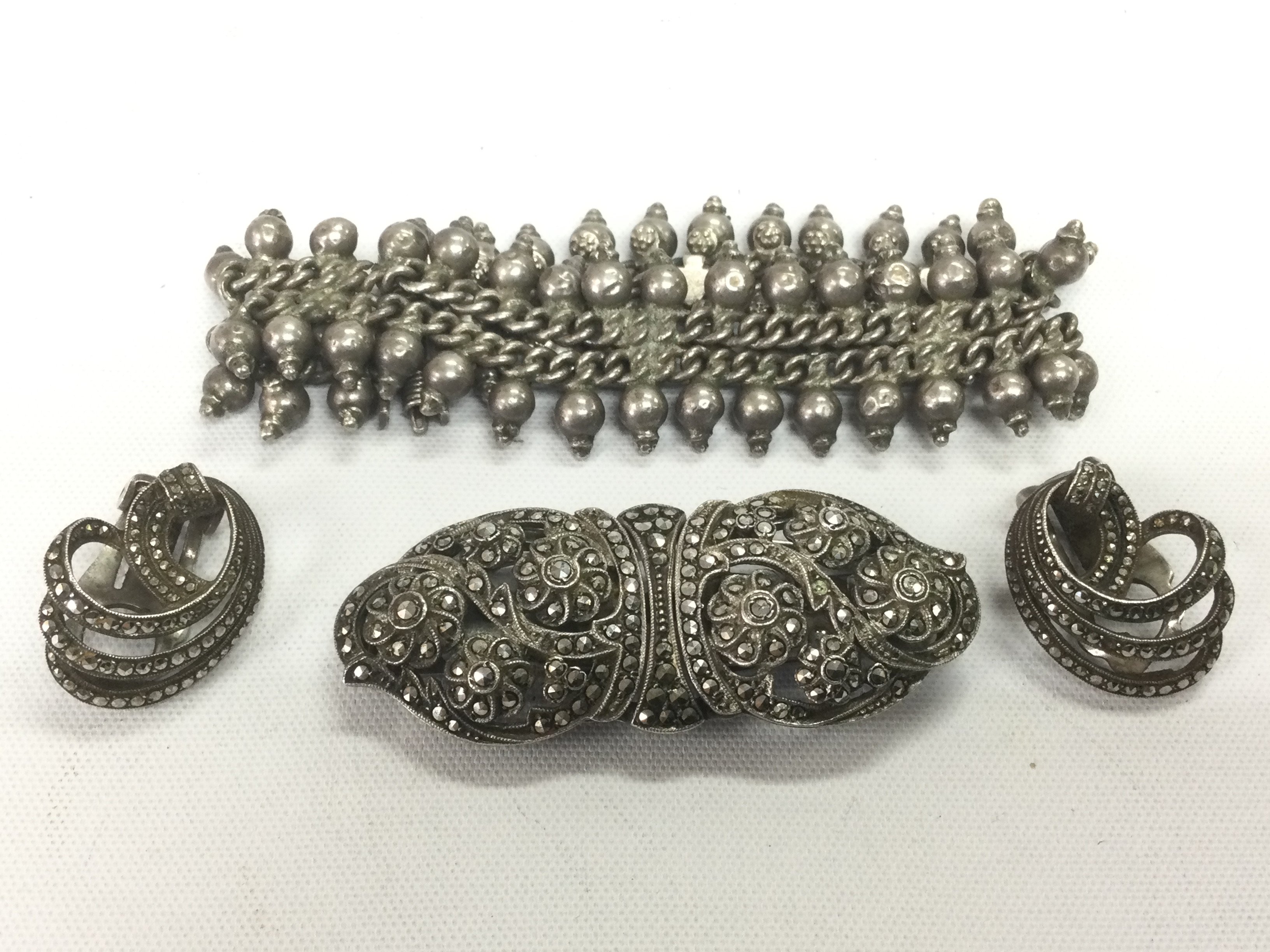 A silver bracelet, a pair of marcasite earrings and a brooch. Shipping category A.