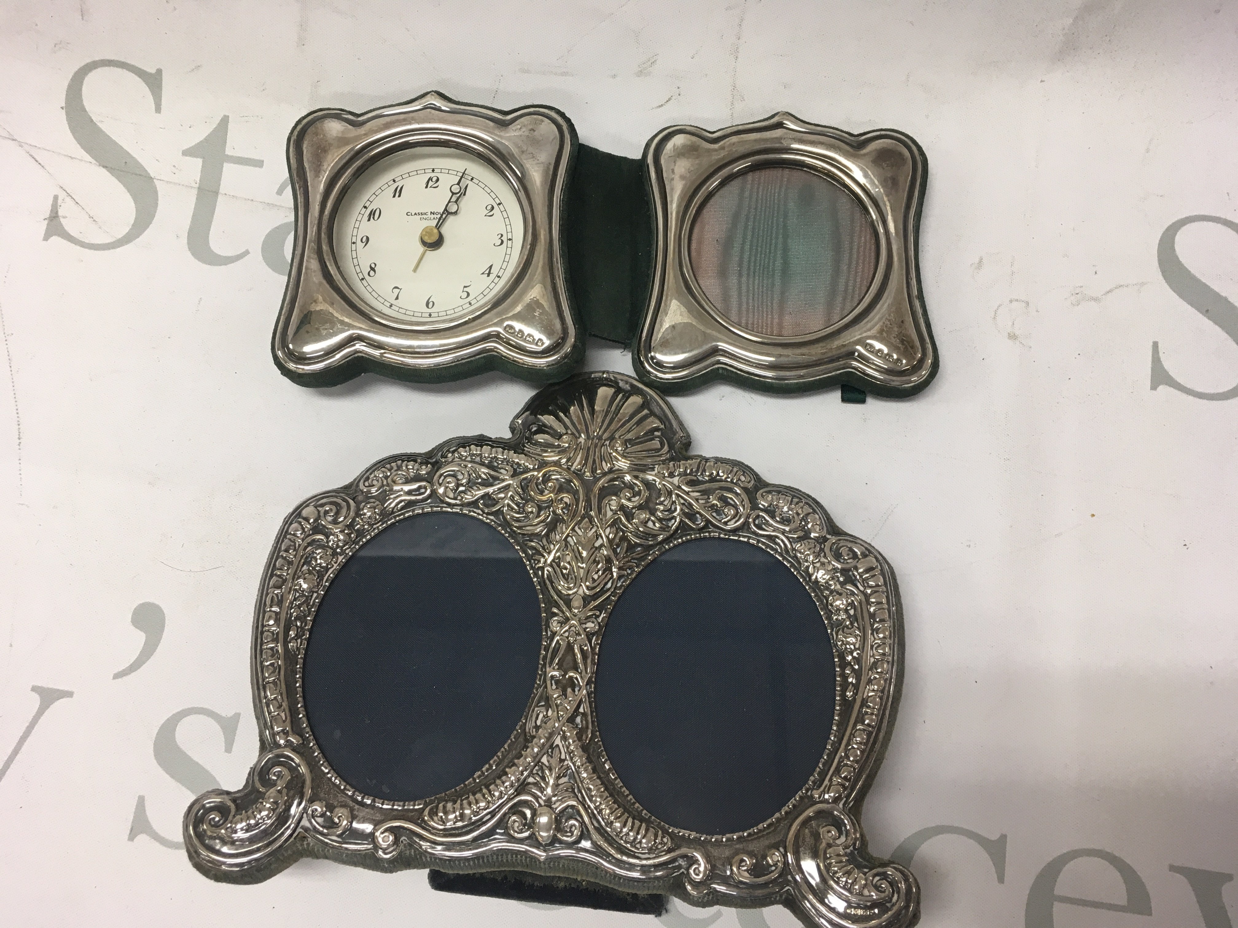 A silver double photo frame together with a silver desk clock and photo frame.