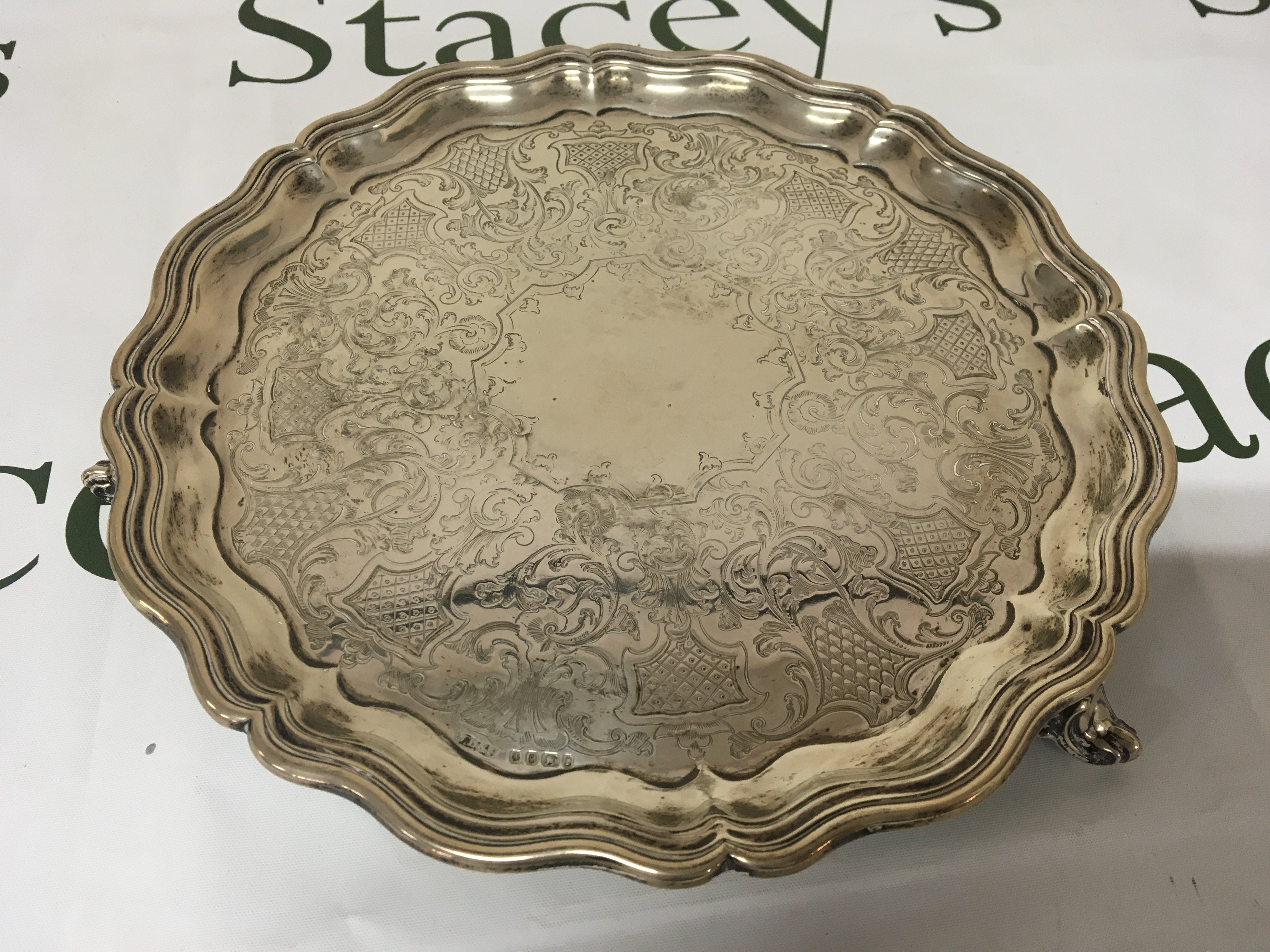 A Victorian silver tray with a shaped edge and scroll feet Sheffield hallmarks.diameter 26cm. Weight 560g