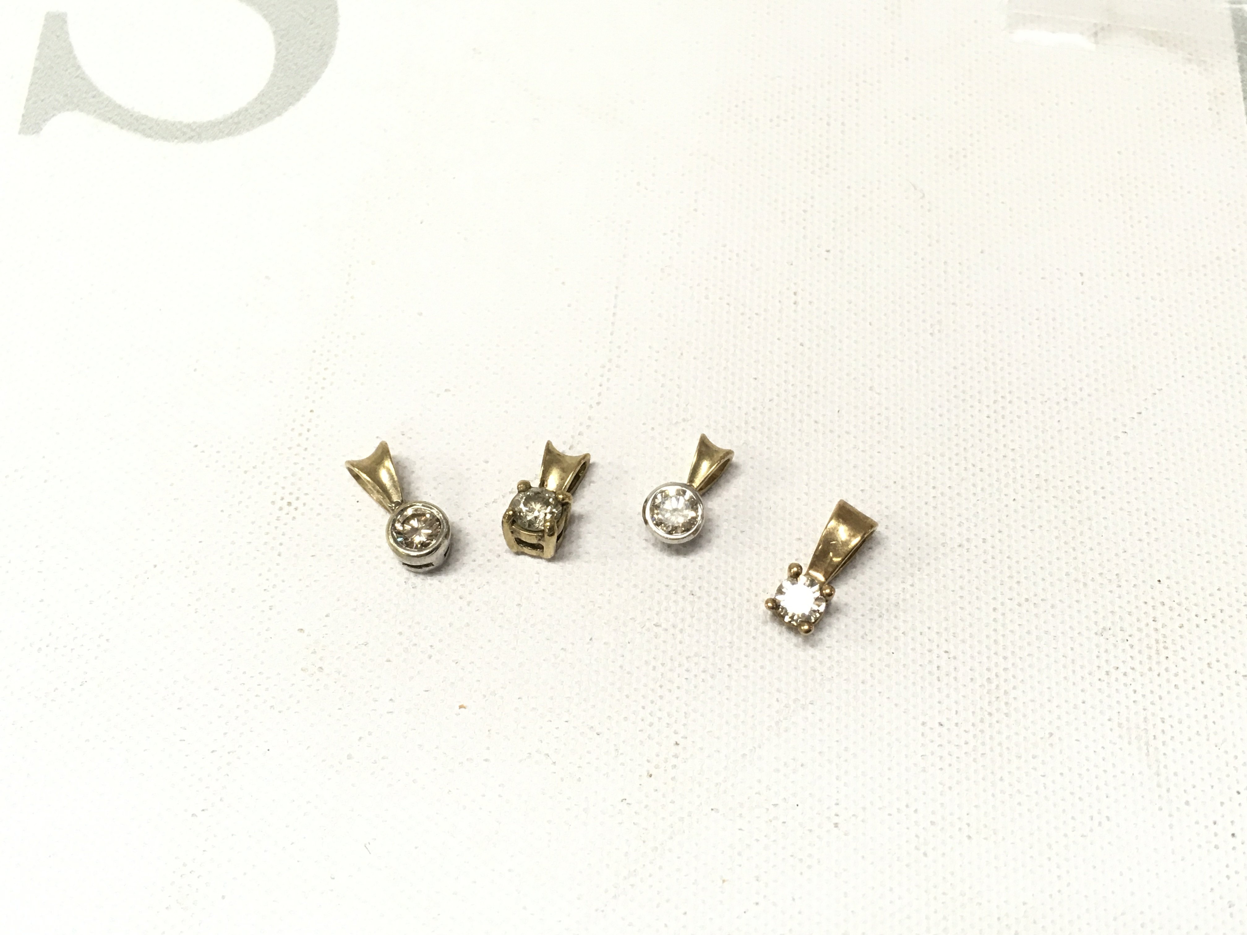 Four 9ct gold diamond solitaire pendants. Approx weight 1.9grams.