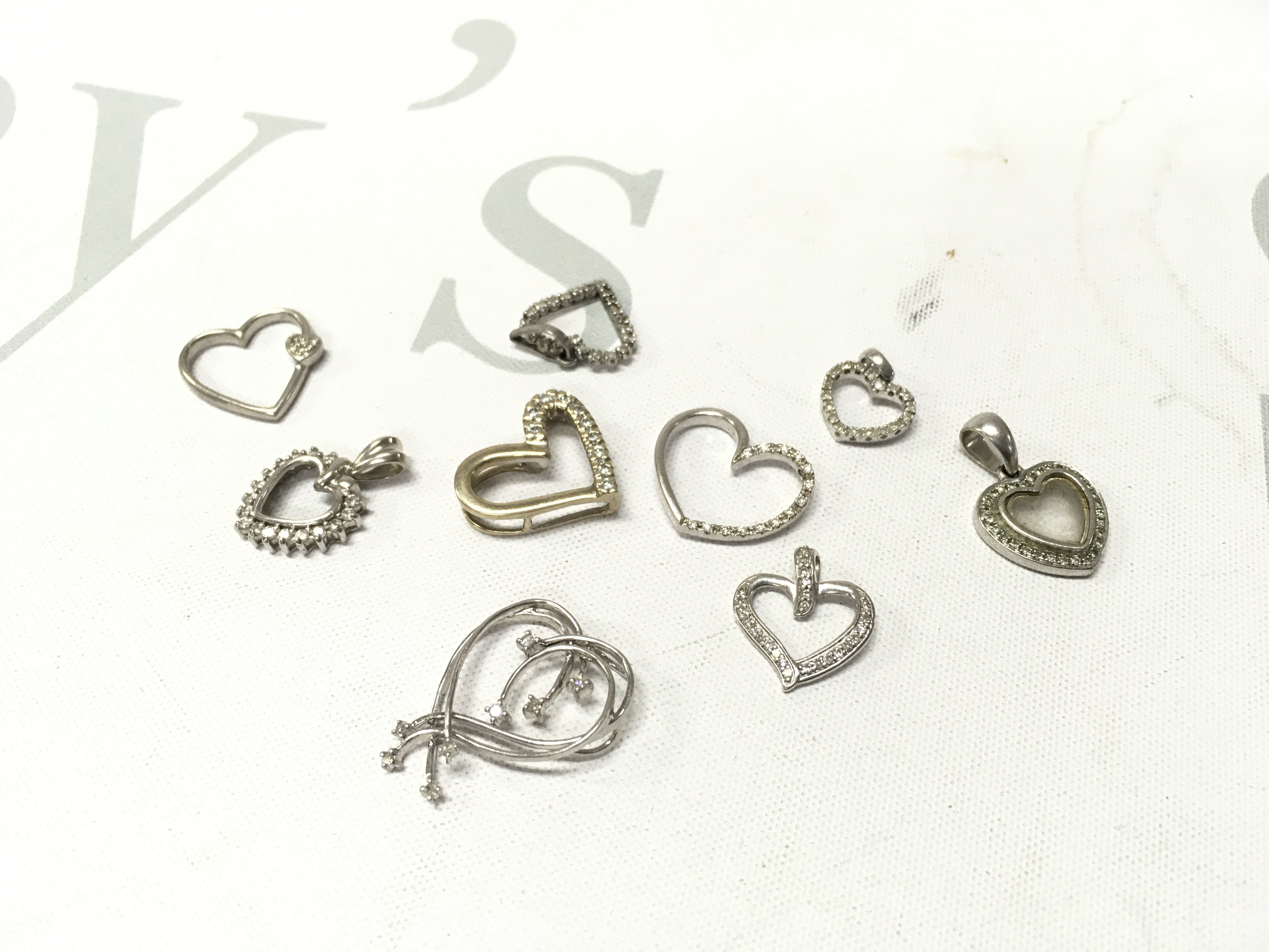 A mixed assortment of mixed carat white gold heart pendants Approx weight 14.7 grams.