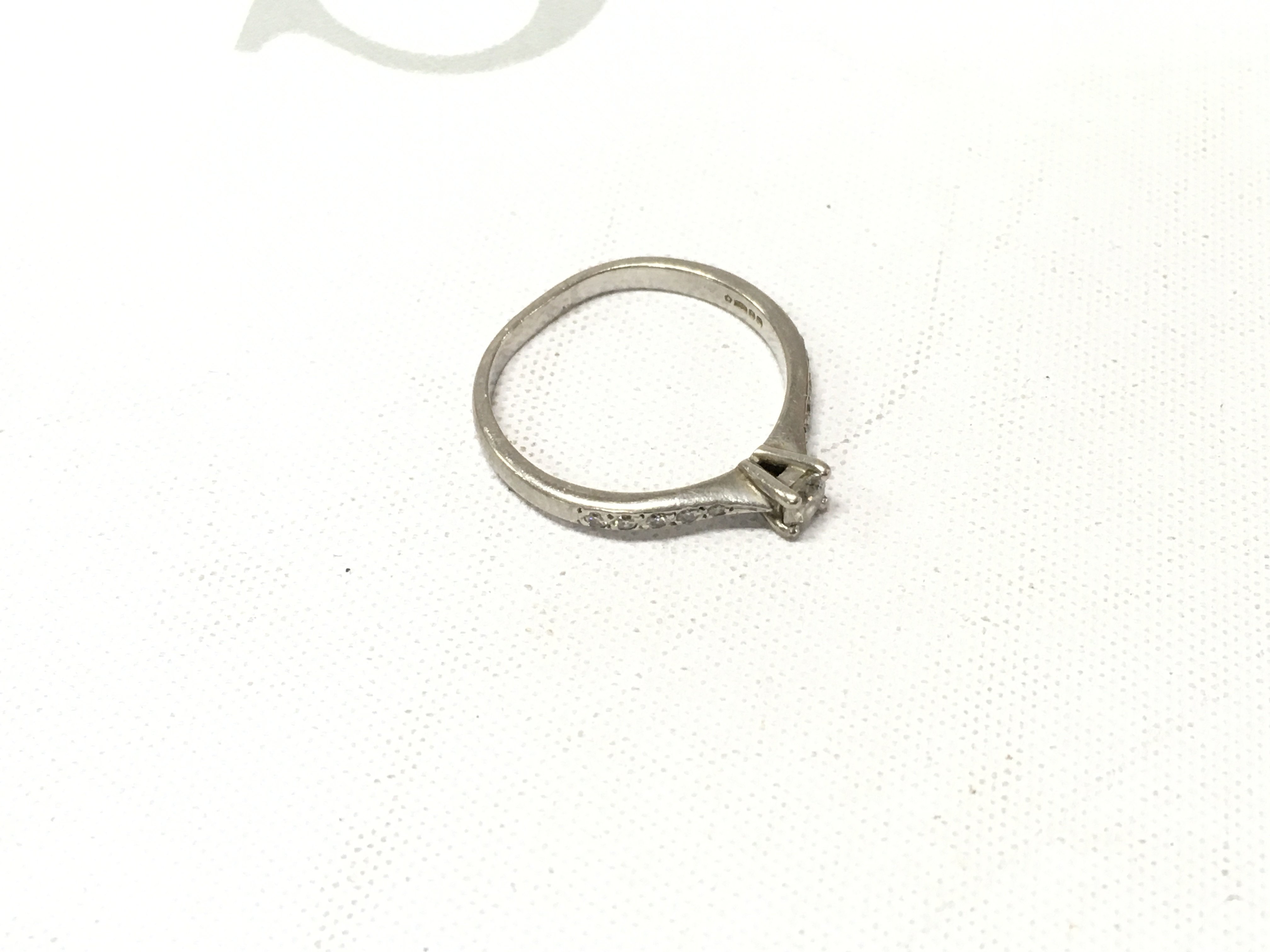 A platinum diamond solitaire ring with stone set shoulders. Approx weight 3.1 grams, Approx size N.