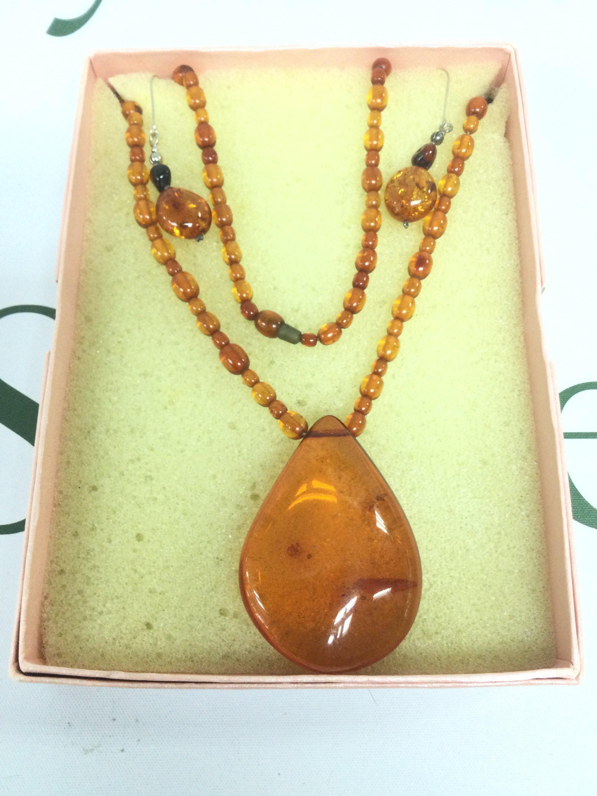An amber beaded necklace and a pair of matching earrings. Shipping category A.