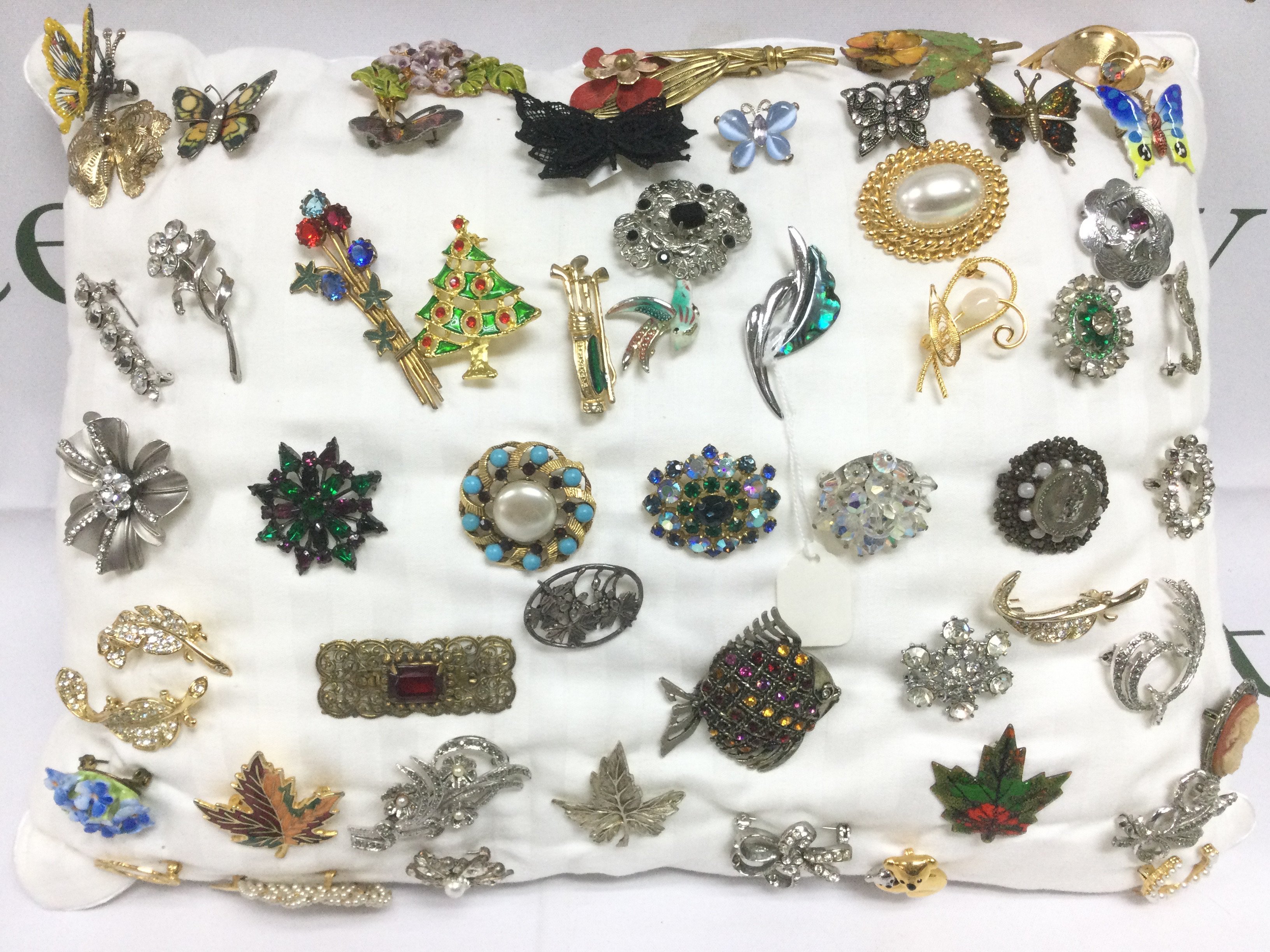 A cushion of brooches, approx 50. Shipping category B.
