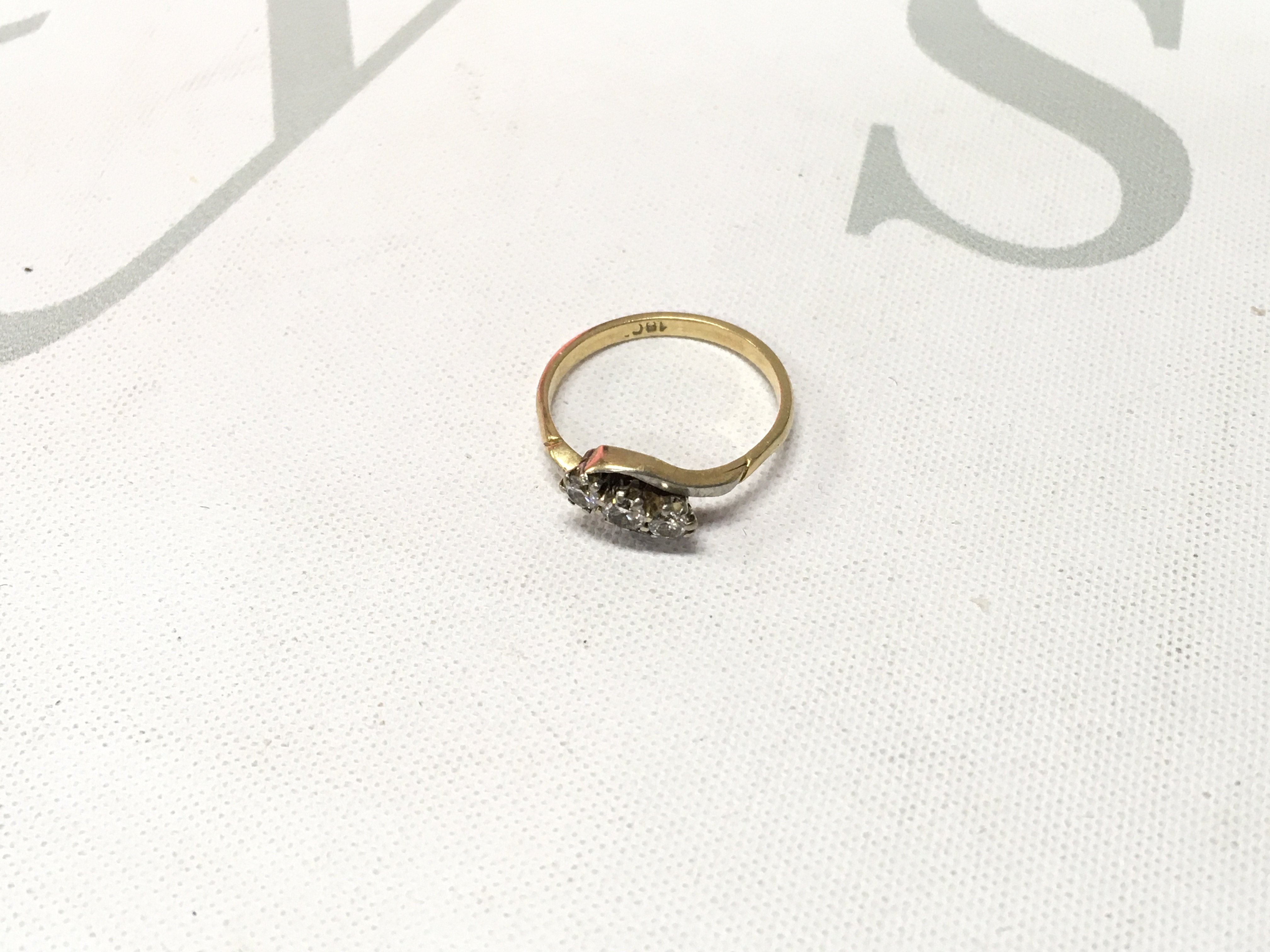 An 18ct gold three stone diamond crossover ring. Approx weight 2.1 grams, Approx size J.