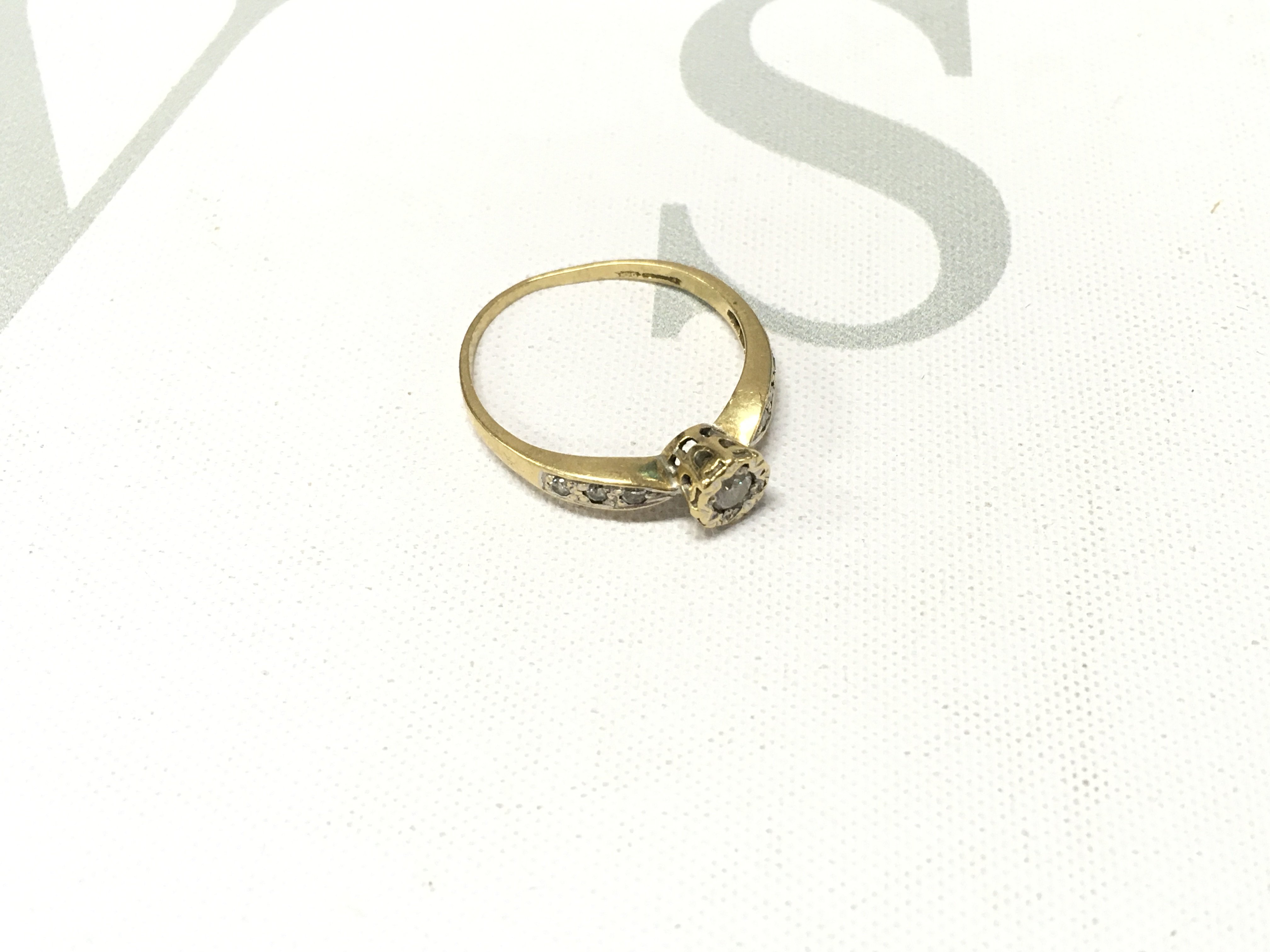 An 18ct gold solitaire ring with stone set shoulders. Approx weight 2.4 grams, Approx size P.