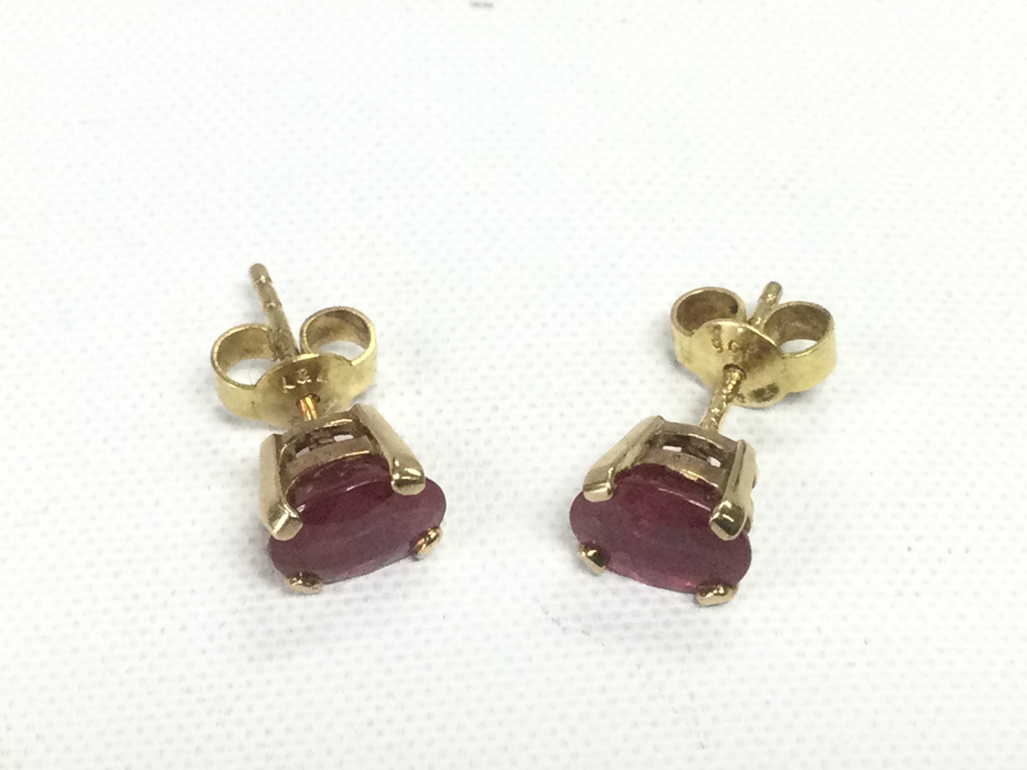 A pair of 9ct gold oval cut solitaire ruby studs, approx 1.1ct, red SIP/6/5. Approx 1.8g. Shipping category A.
