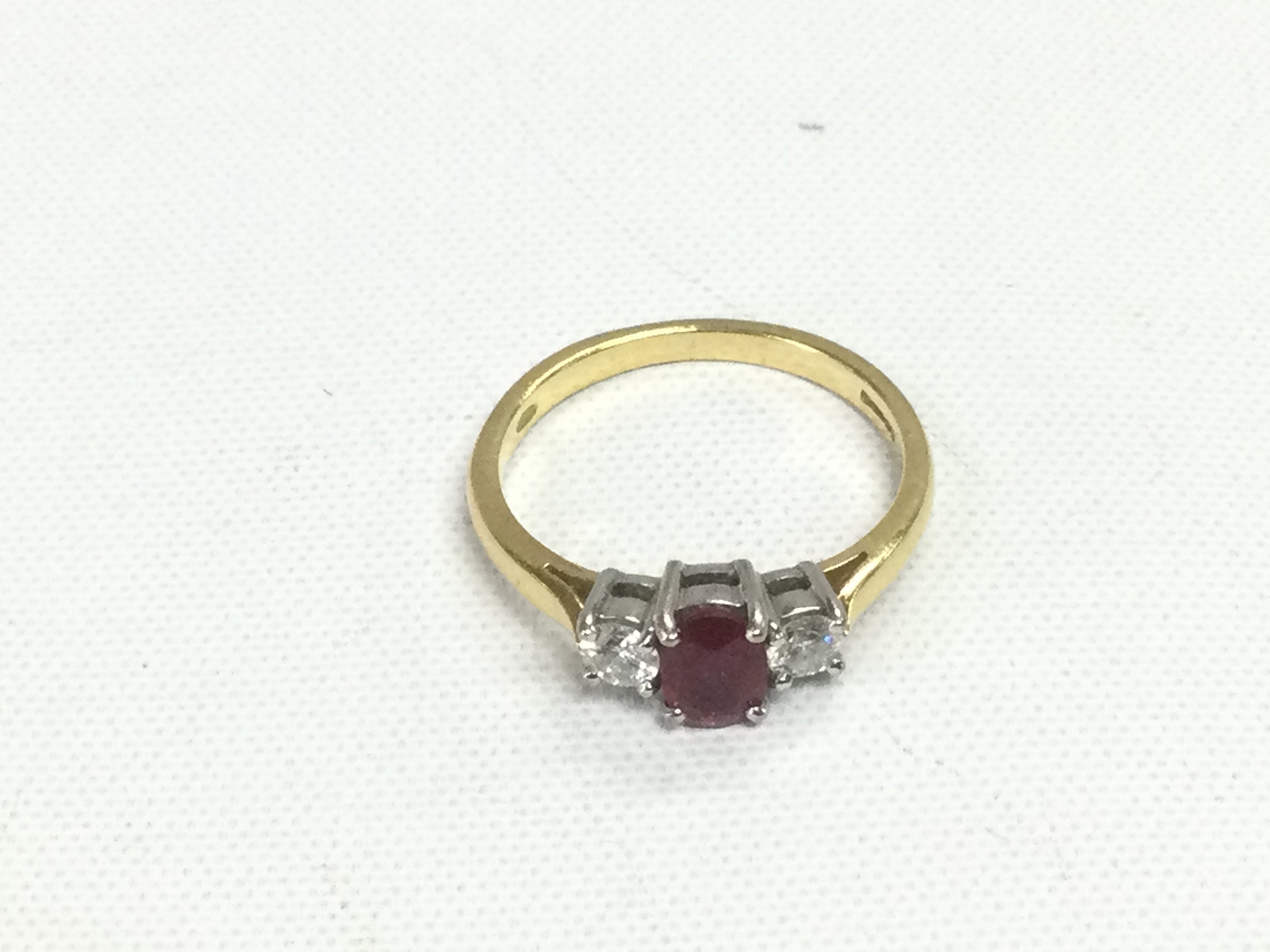 An 18ct gold, ruby and diamond three stone ring, VS2 G/H. Approx 2.6g and approx size J-K. Shipping category A.