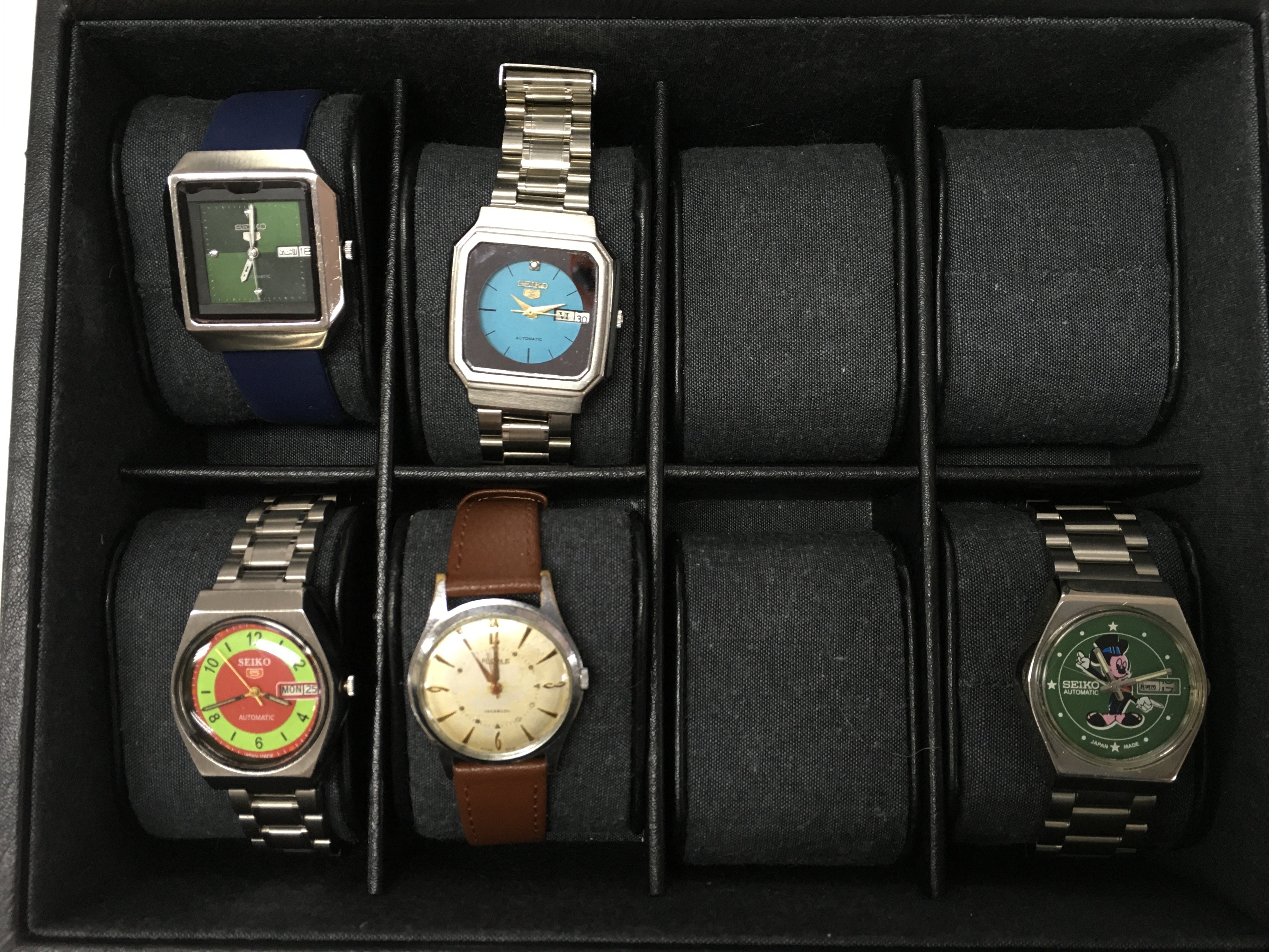 Watches including Seiko 5 automatic Arabic day/date, vintage Seiko 5 green face, Rone Gents wrist watch, Vintage Seiko Emerald green TV dial and a Seiko Automatic Mikey Mouse face Japan made watch. Stored in a watch case. Postage category B
