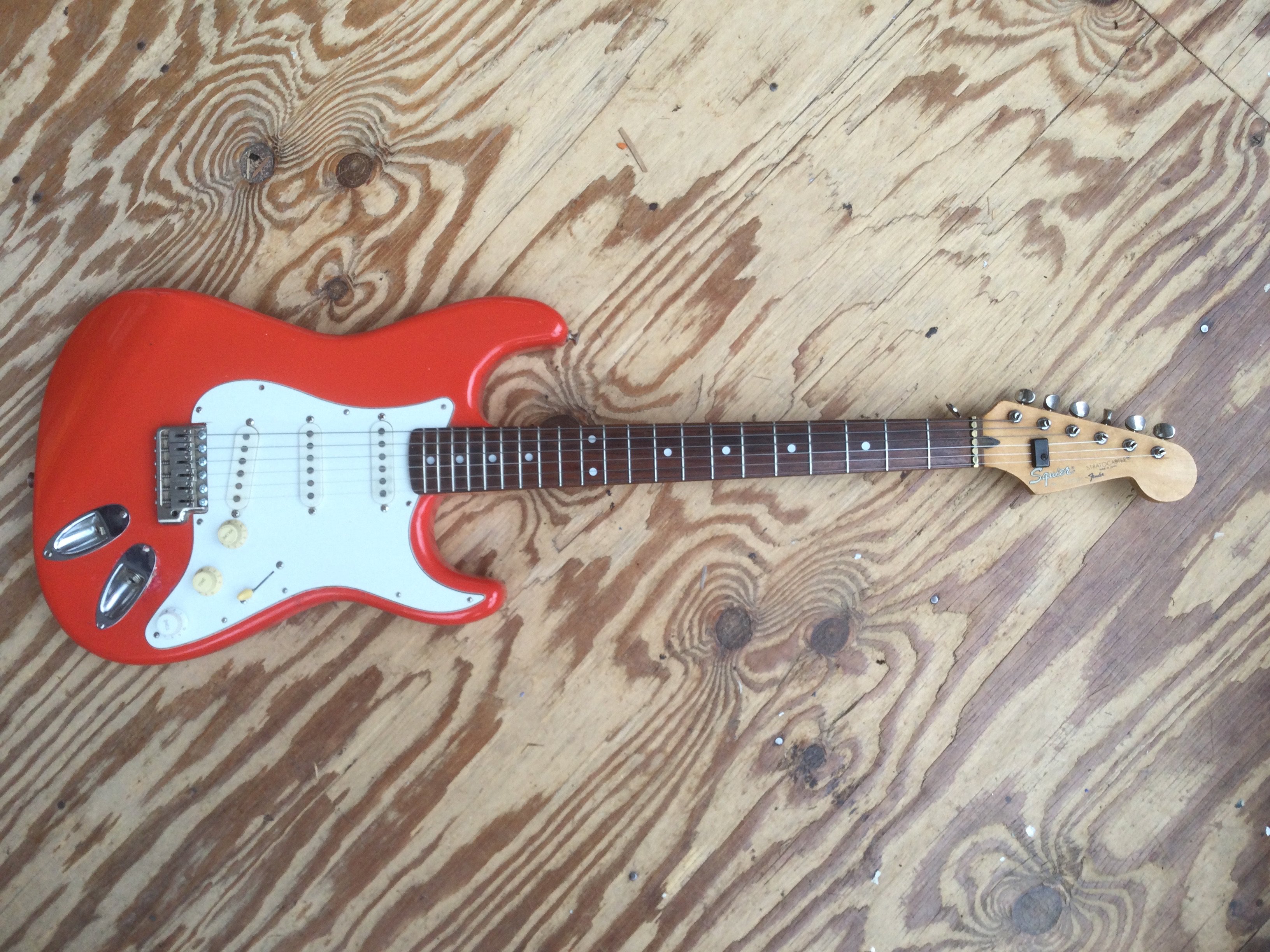 A Japanese Fender Squier Stratocaster electric guitar. Some repairs to the body and alteration to the tuners. No case.