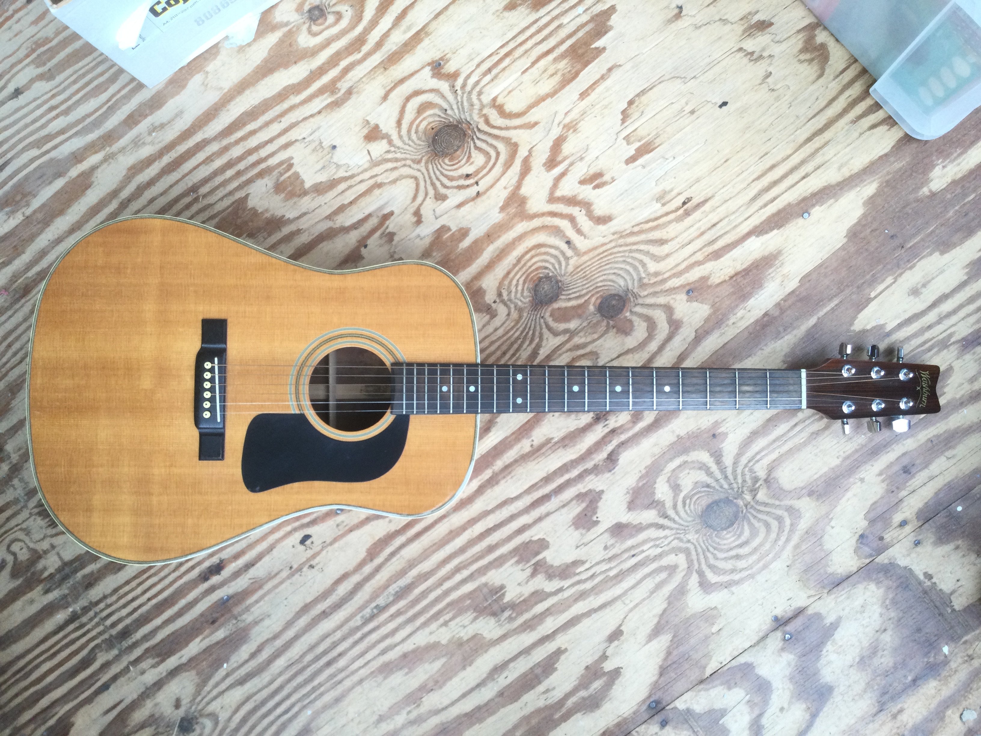 A Washburn D13-N acoustic guitar. Comes with a soft carry case.