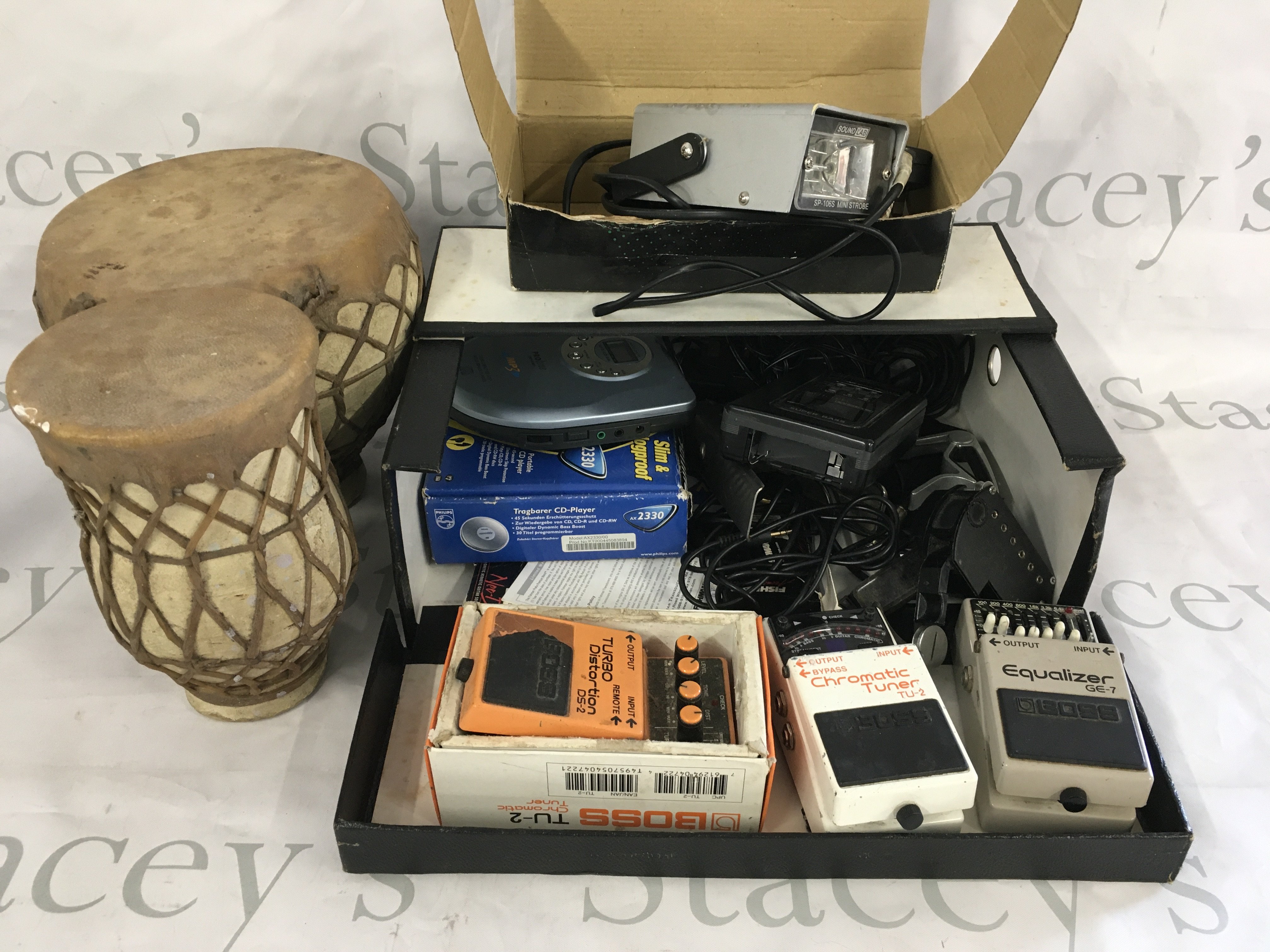 A box of miscellaneous items comprising Boss guitar pedals, a pair of bongos etc.