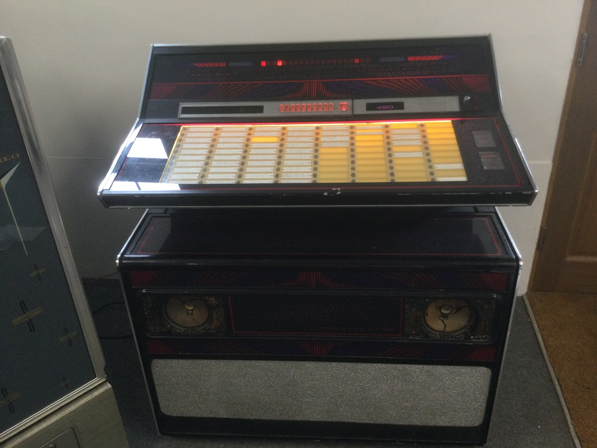 A Rock Ola 460 jukebox. Powers up and turntable spins but speaker cones are damaged. No sound. In need of restoration.