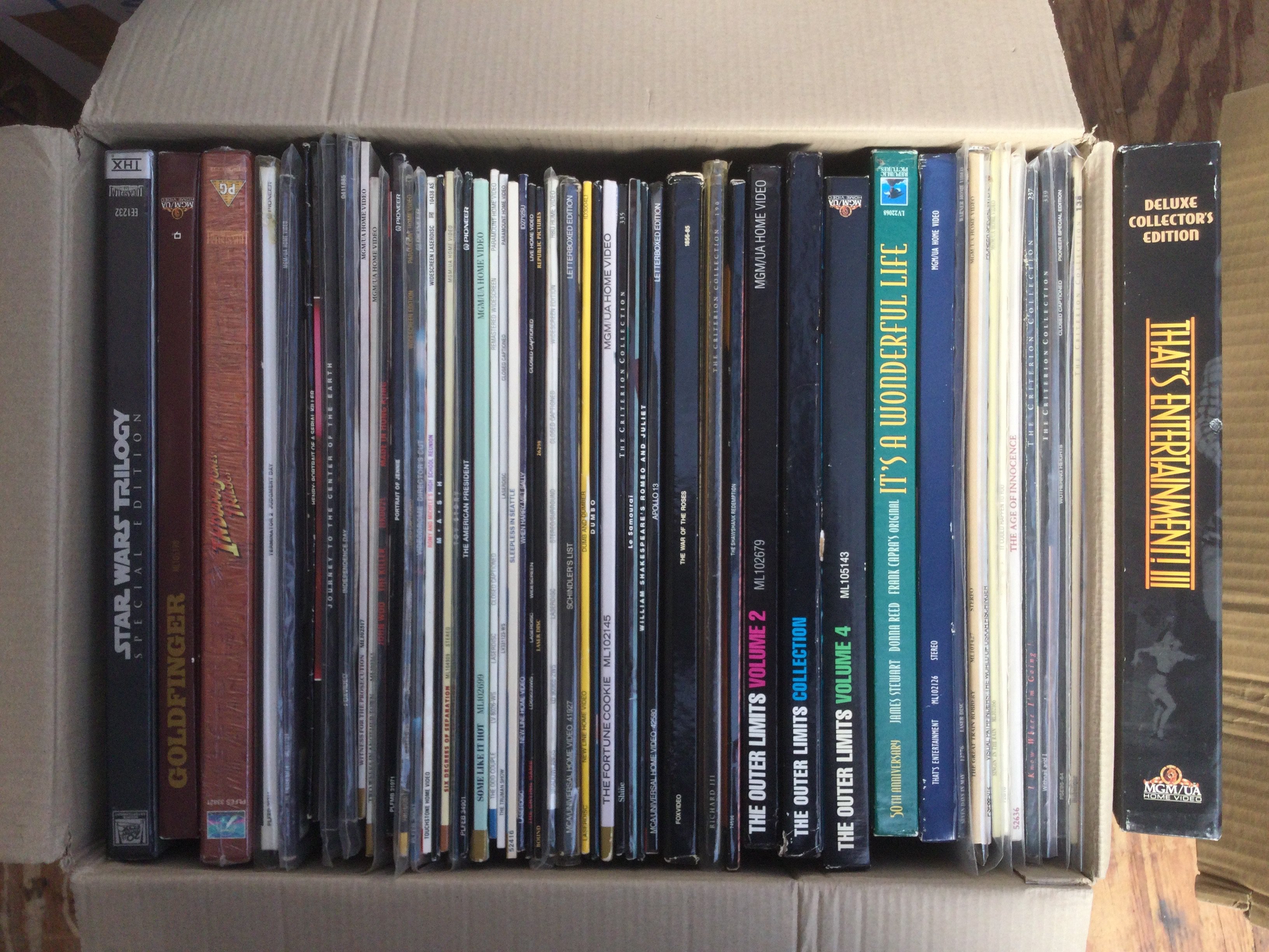 Two boxes of laser discs comprising the original Star Wars Trilogy, Three volumes of The Twilight Zone, An Indiana Jones Trilogy etc