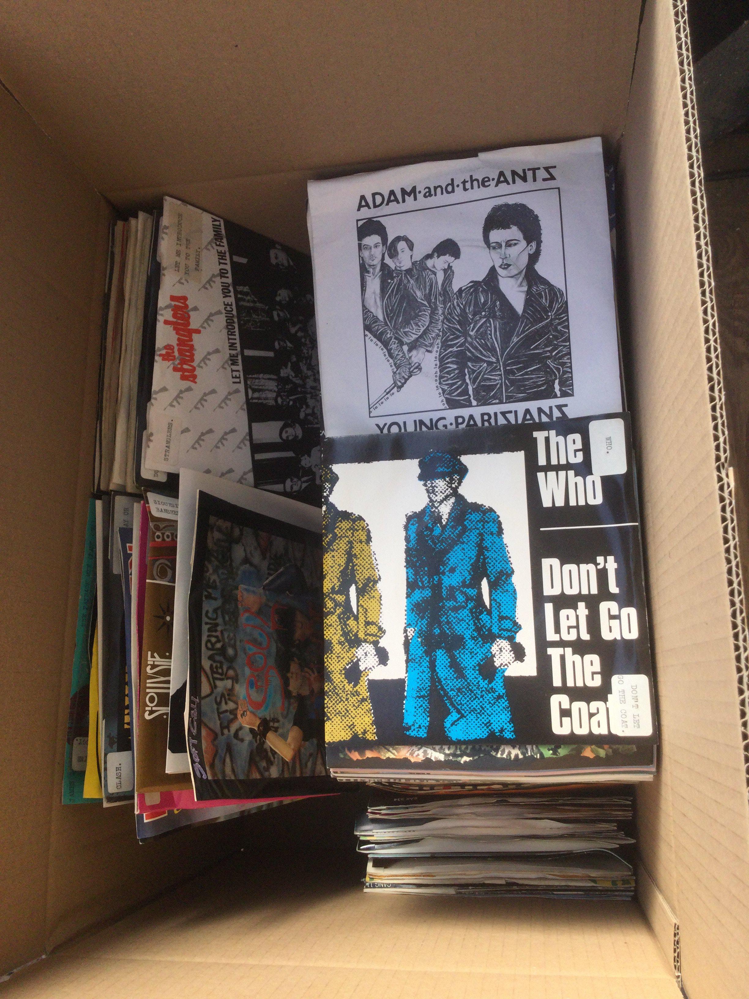 A box of 7" singles by various artists including Iron Maiden, Siouxsie& The Banshees, The Stranglers, The Clash and many more.