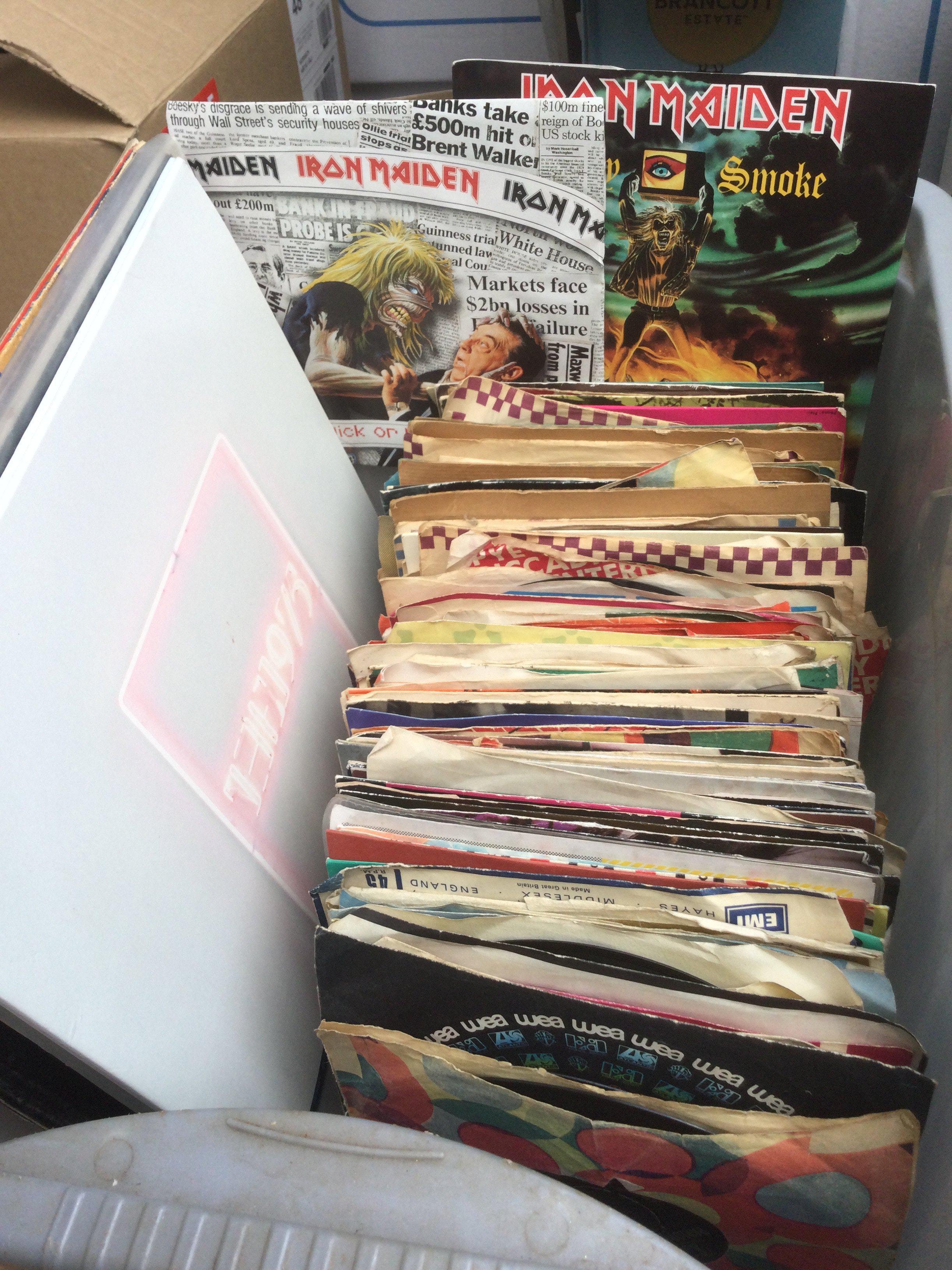 A collection of 7" singles and LPs by various artists including a clear vinyl 1975 LP, Iron Maiden, The Beatles and others.