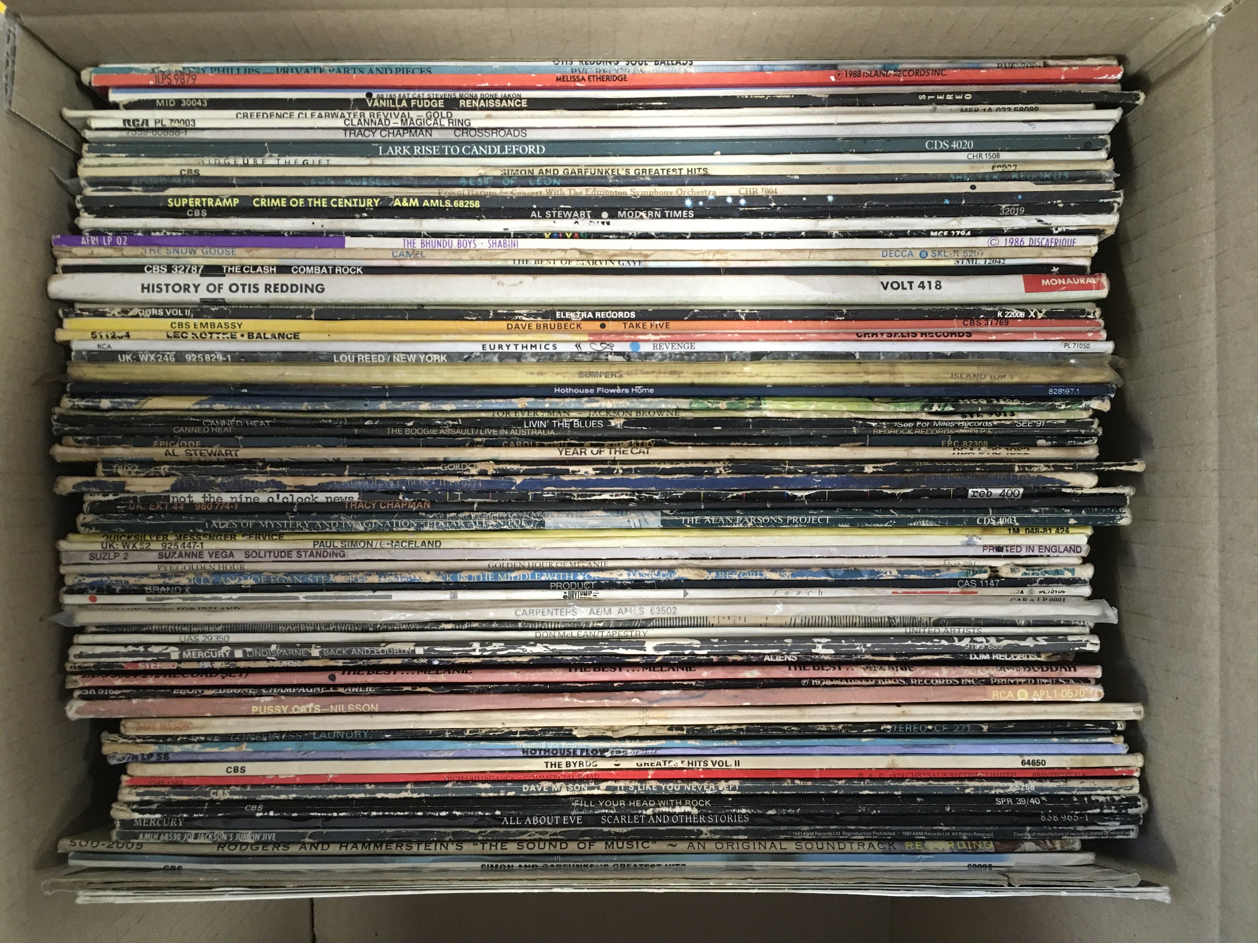 A box of LPs and cassettes by various artists including The Clash, AC/DC, The Byrds and many more.