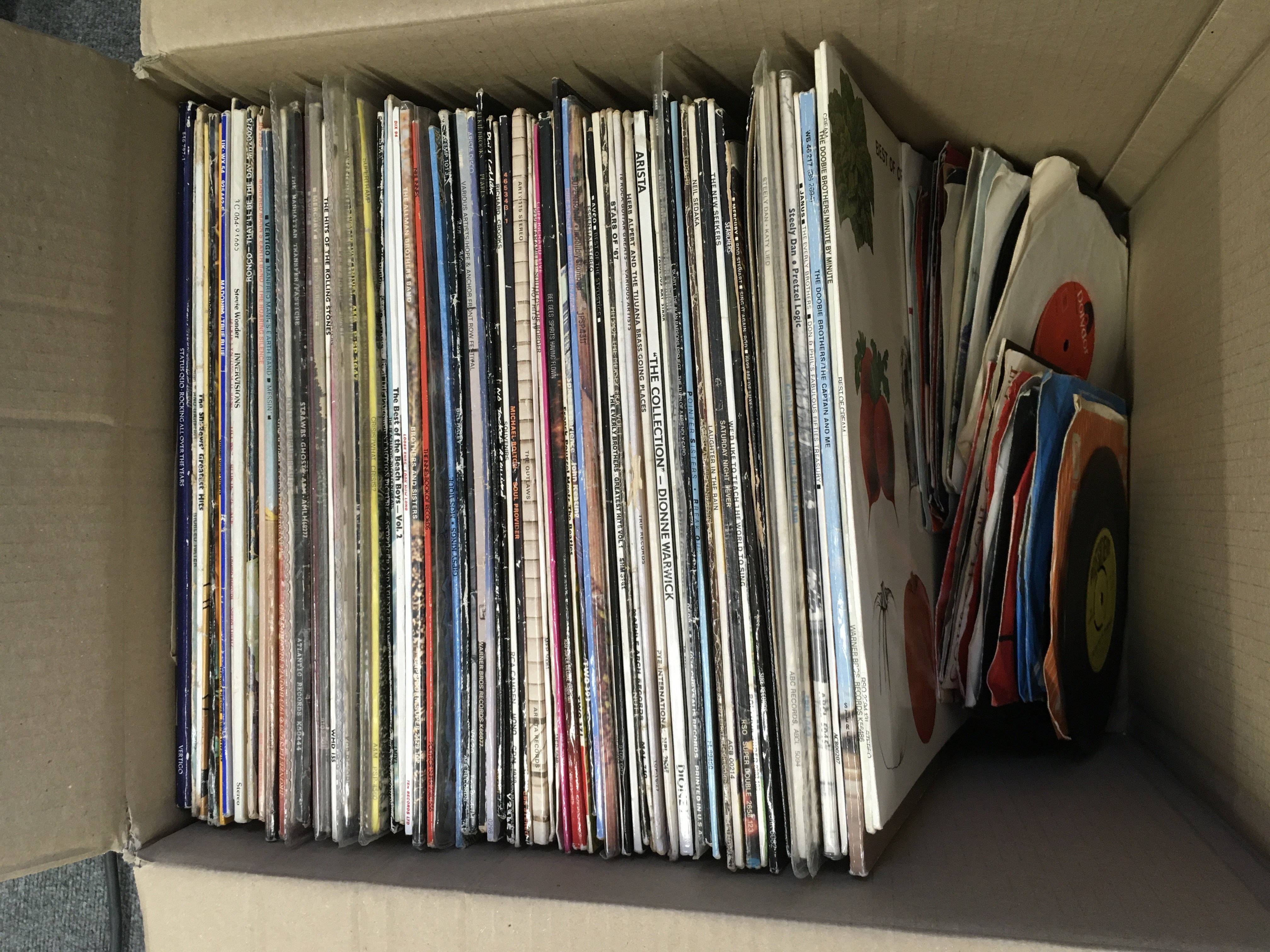 A box of LPs, 12" and 7" singles by various artists including Cream, Steely Dan, Manfred Mann's Earth Band and others.