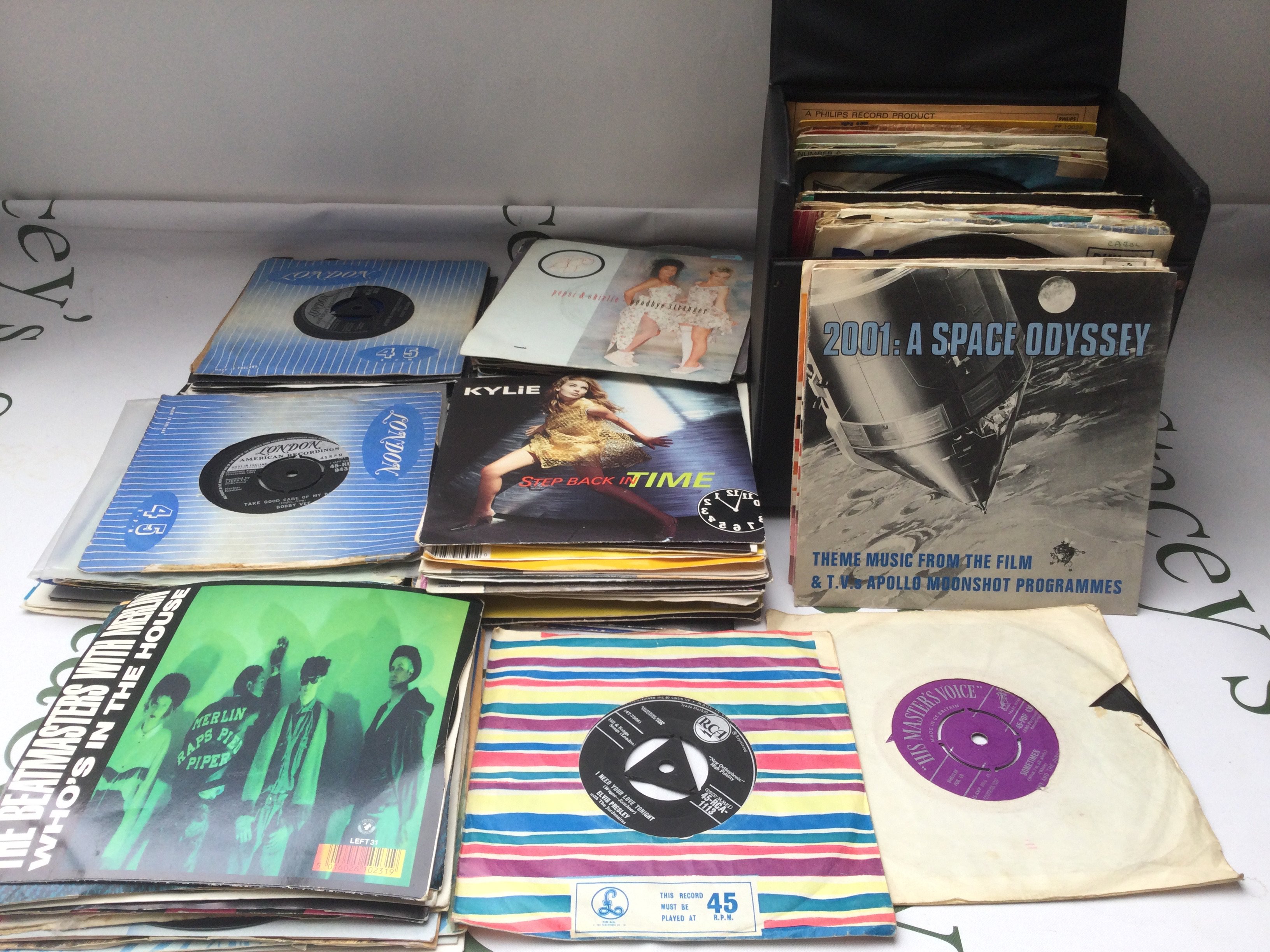 A record case and a bag of 7" singles and EPs by various artists from the 1950s onwards.