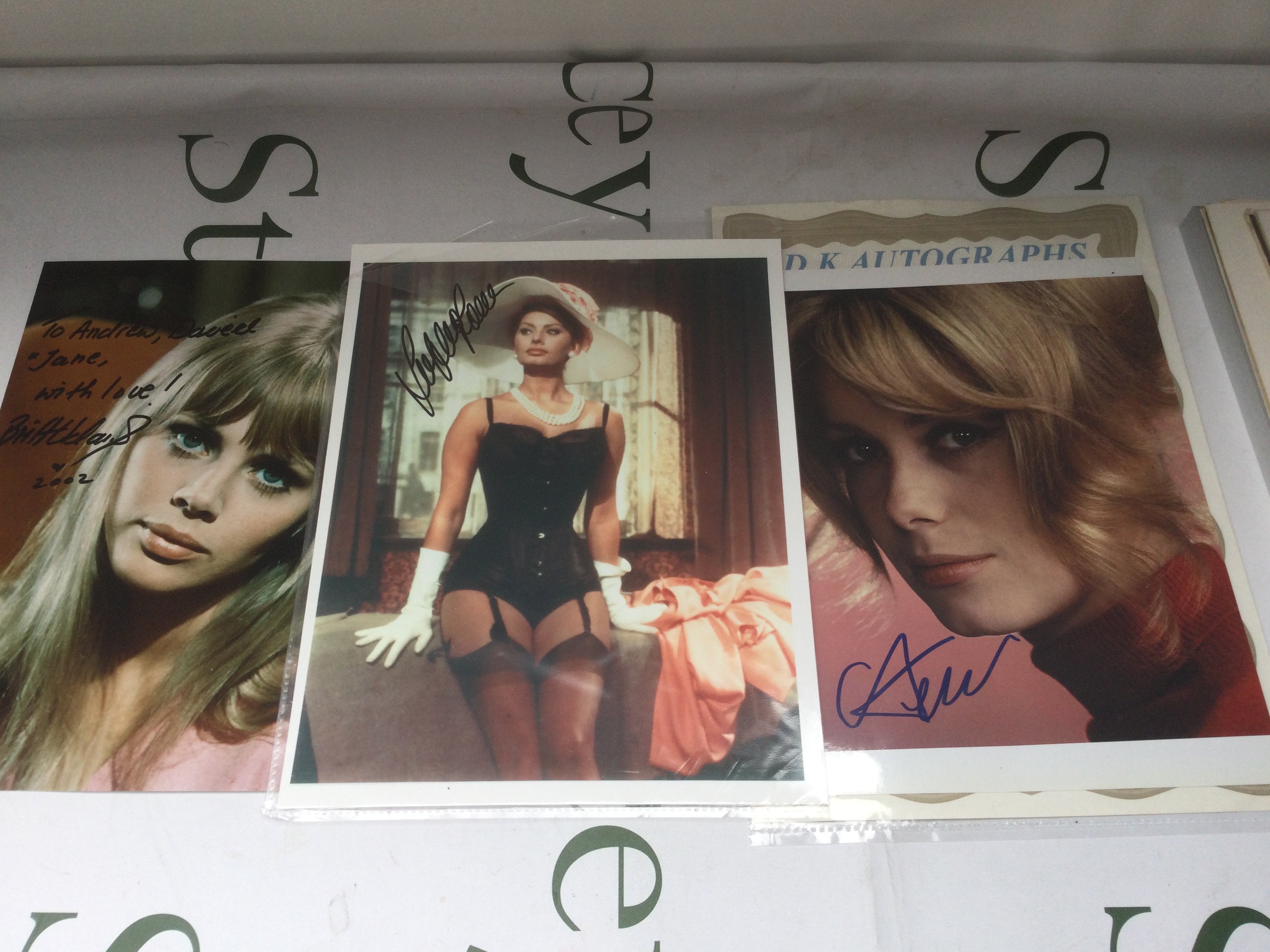 Three signed photos of actresses comprising Sophia Loren, Britt Ekland and Catherine Deneuve plus a Sophia Loren autograph on a booklet page.