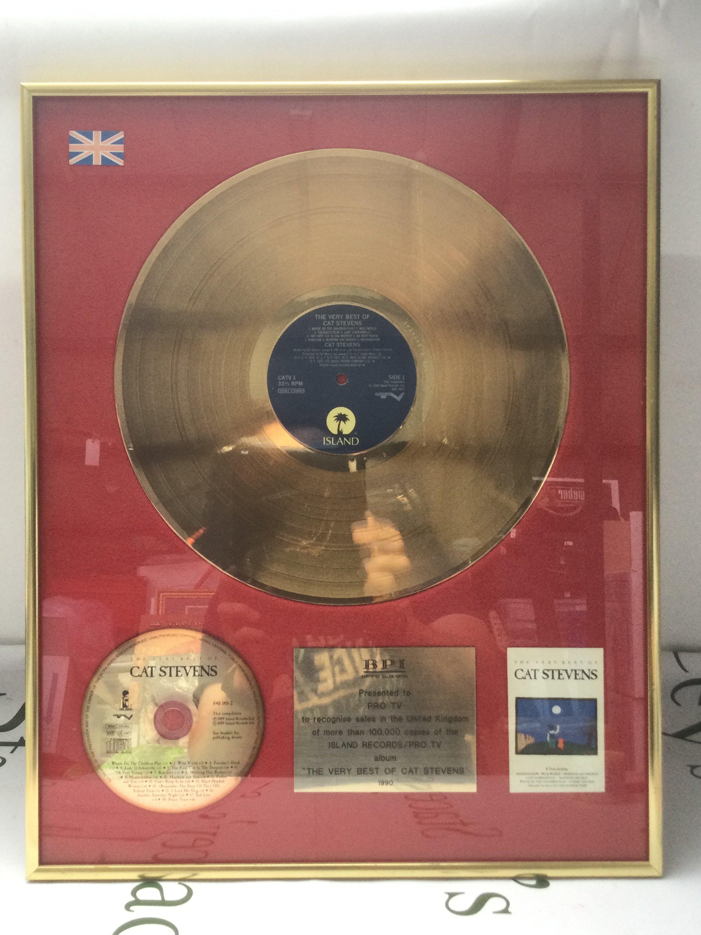 A framed and glazed gold disc of The Very Best Of Cat Stevens, approx 41cm x 51cm.