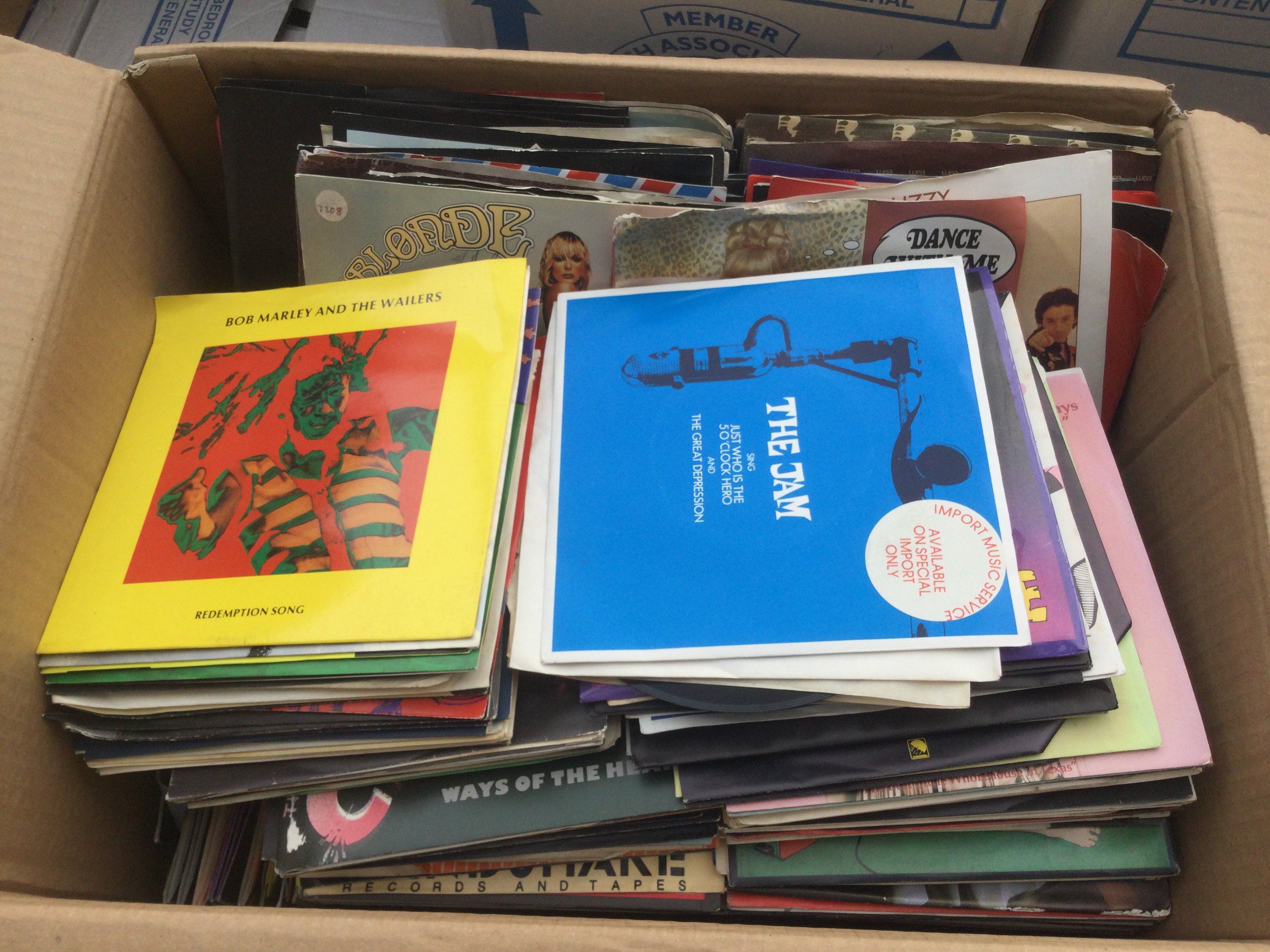 Two boxes of 7" singles by various artists including The Jam, Bob Marley, Bruce Springsteen and many more.