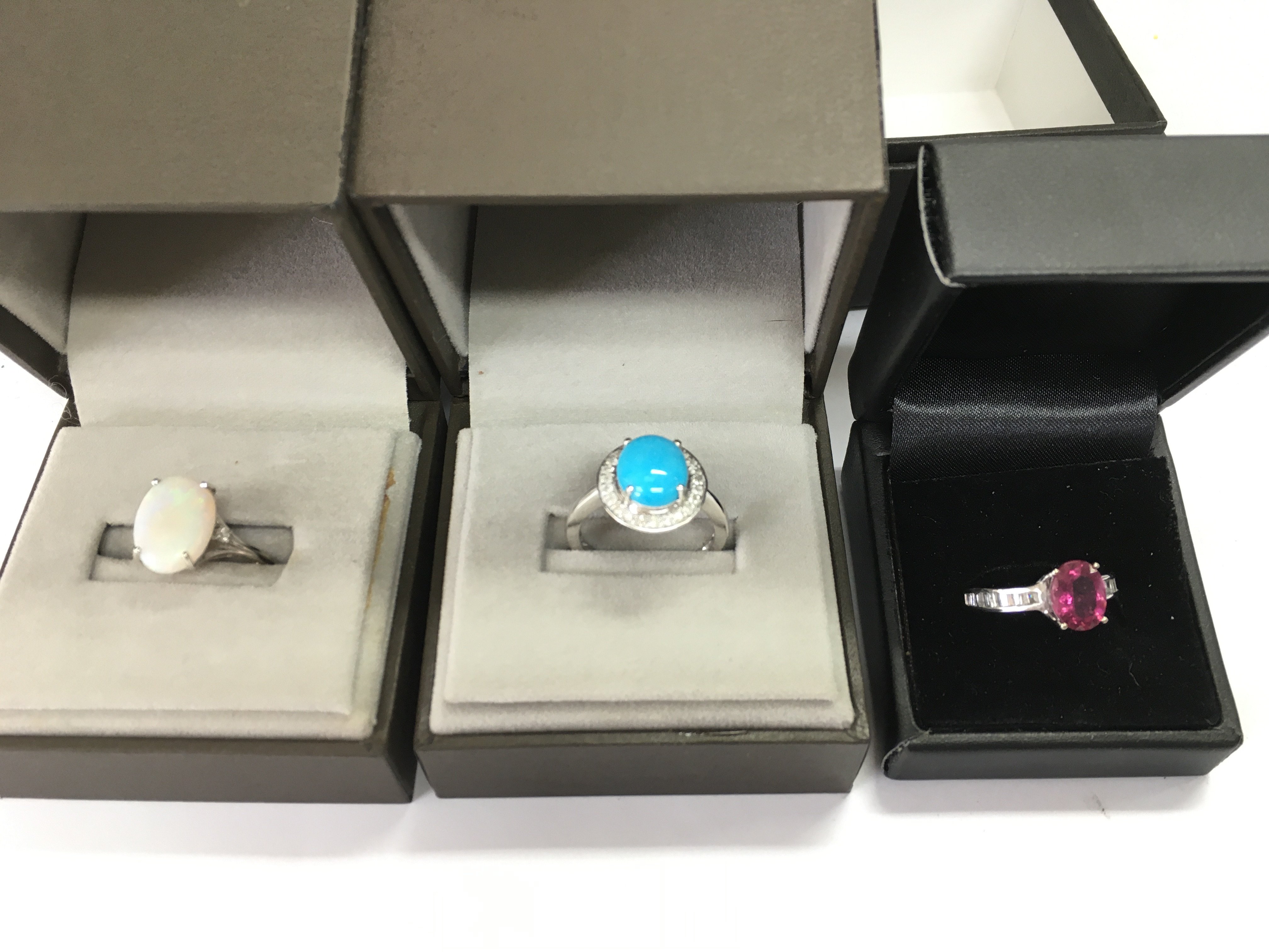 A collection of three 9ct white gold rings set with various stones including opal. 10.48g total weight.
