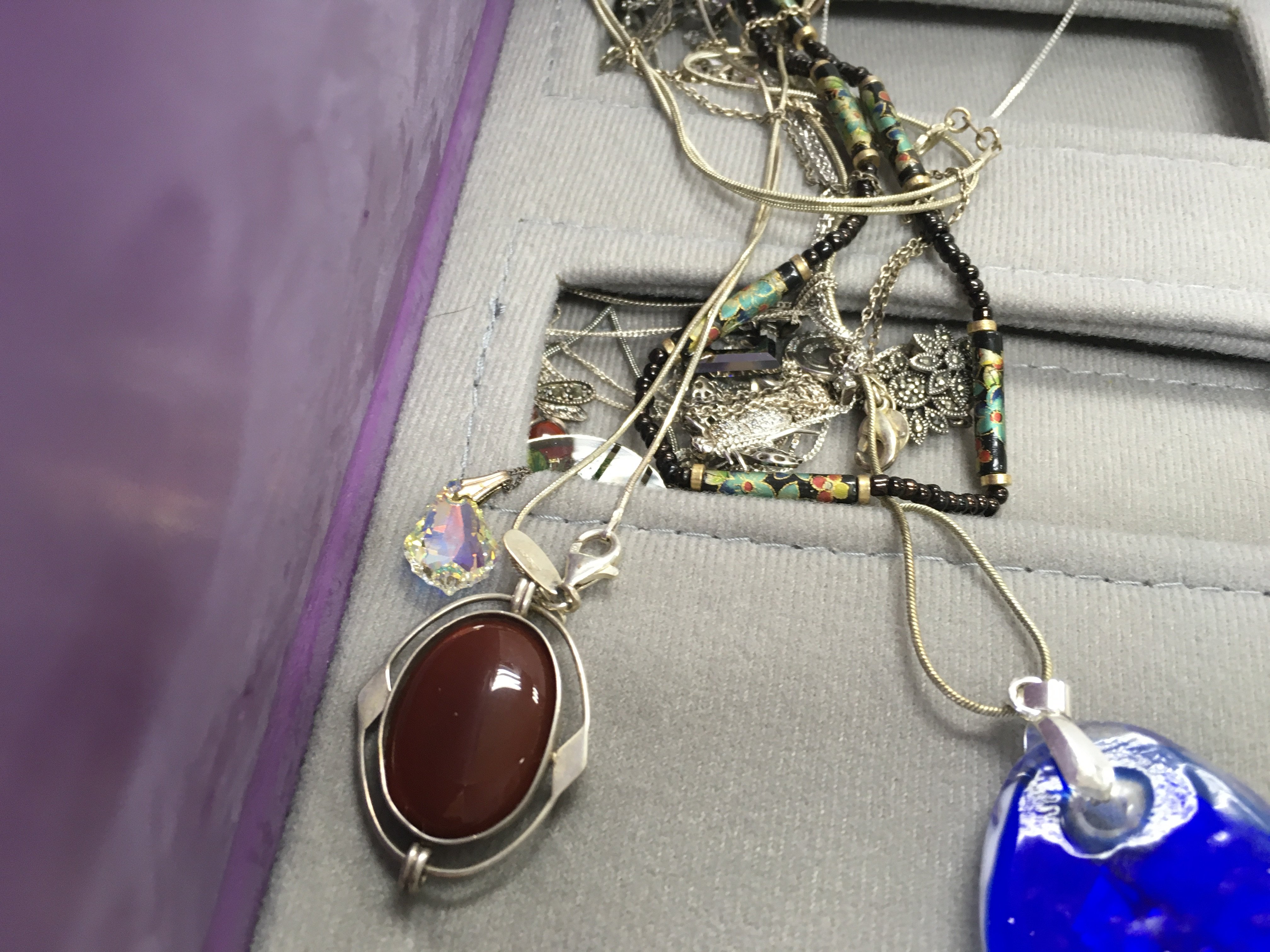 A folder containing various silver and costume necklaces.
