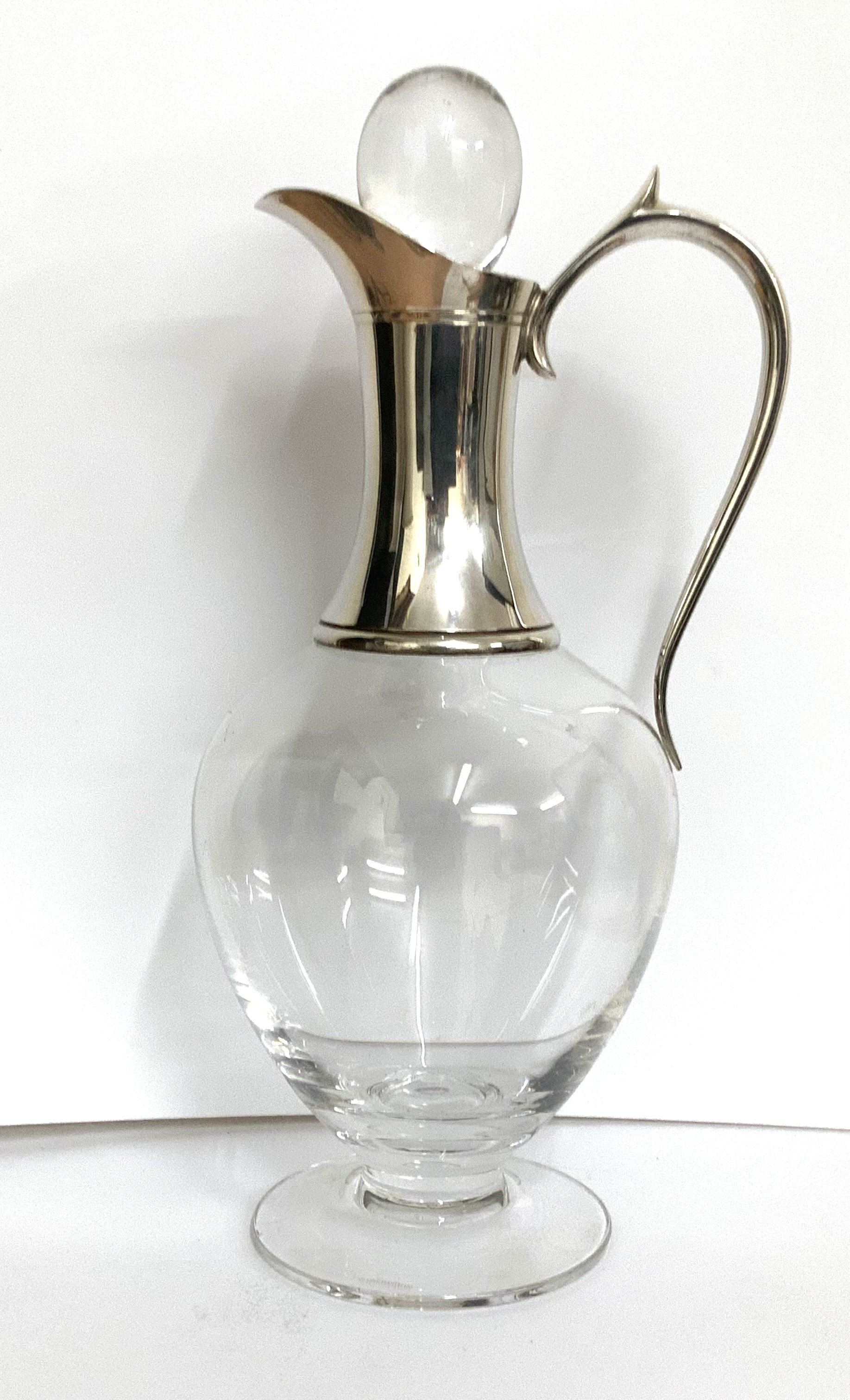 A modern hallmarked silver mounted glass claret jug and stopper with scroll handle, London 1998, height 30.5cm. (D)