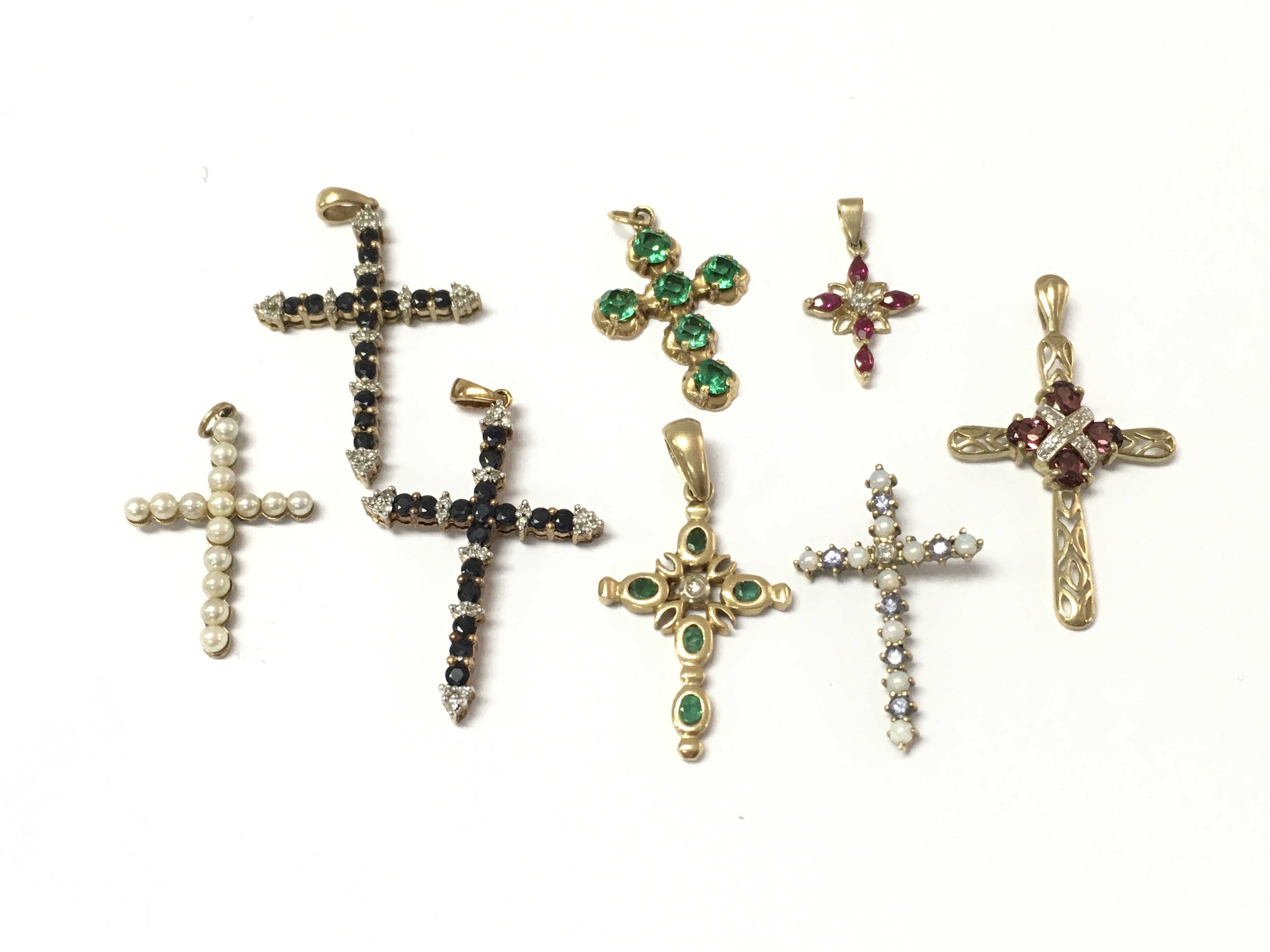 A collection of 9ct gold cross pendants set with assorted stones including diamonds etc. 12.28g