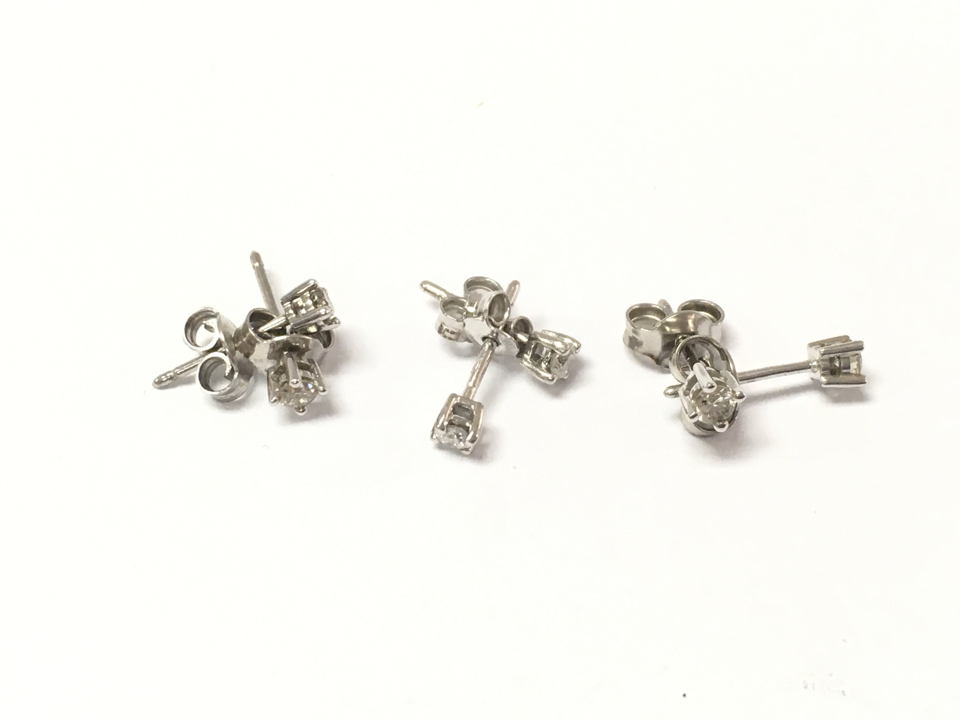 Three pairs of 9ct white gold diamond solitaire earrings. 2.34g