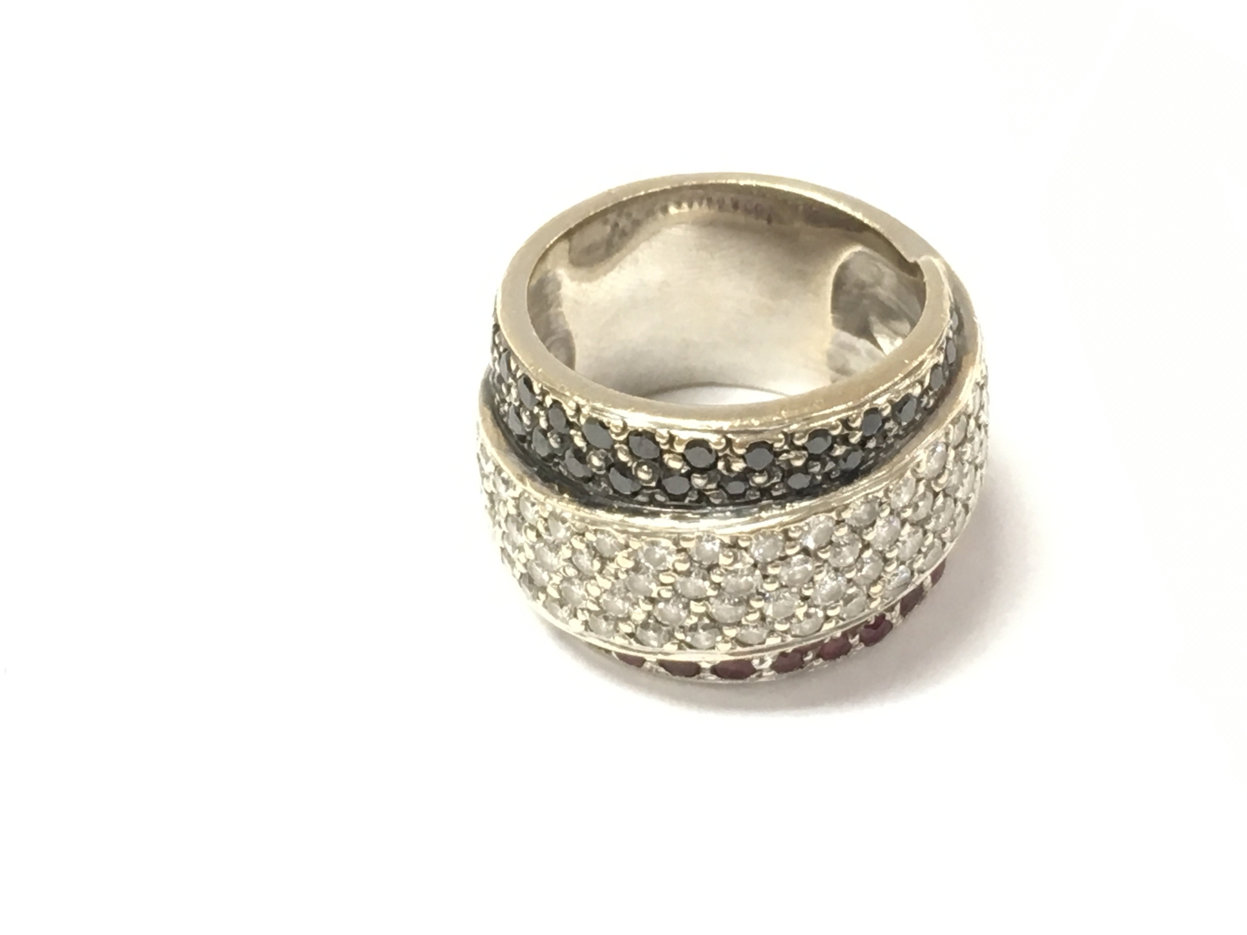 An unmarked white gold ring set with black and white diamonds and red stones. Size M and 17.2g.