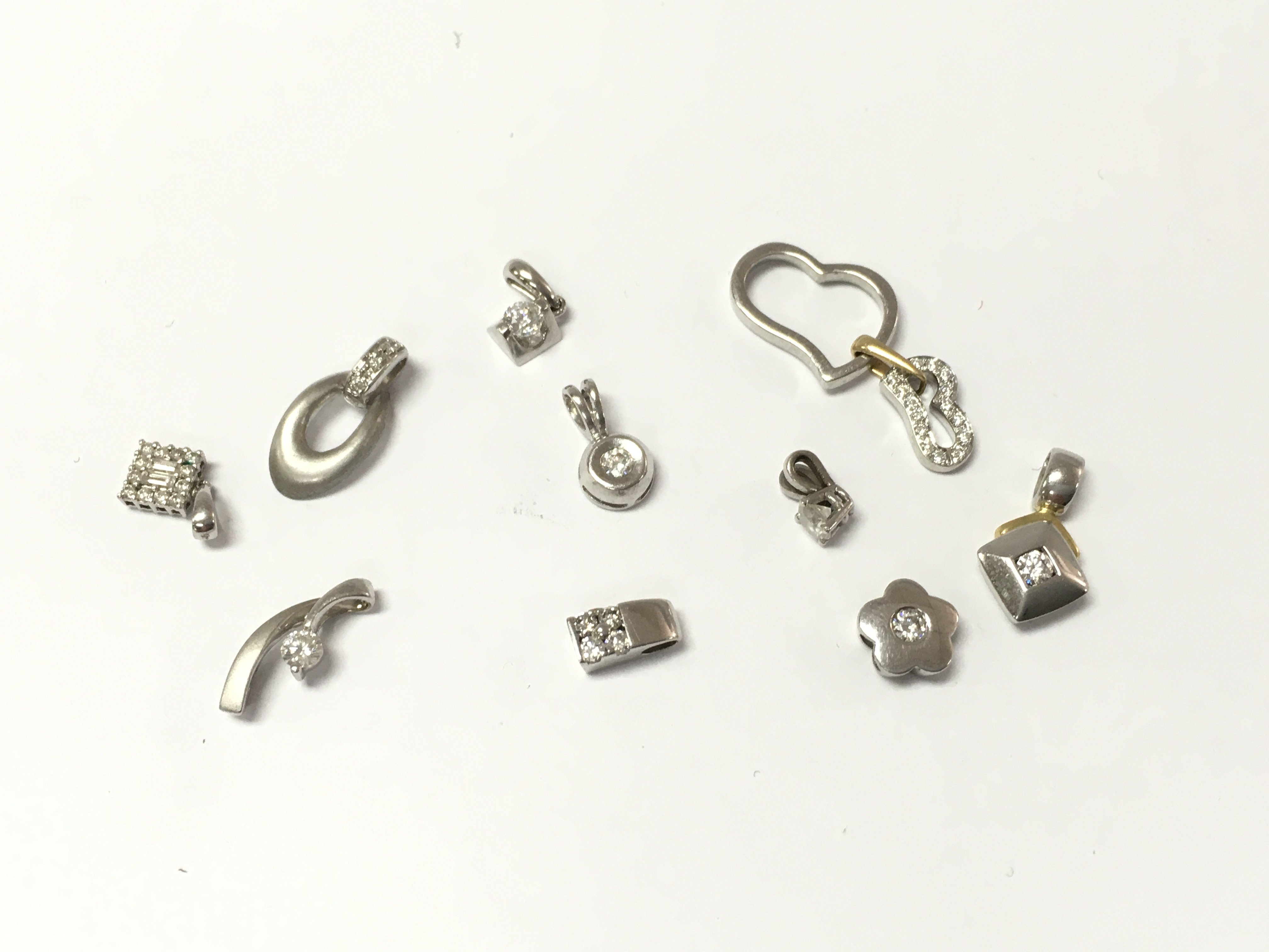 A collection of 18ct white gold diamond pendants. 12.34g