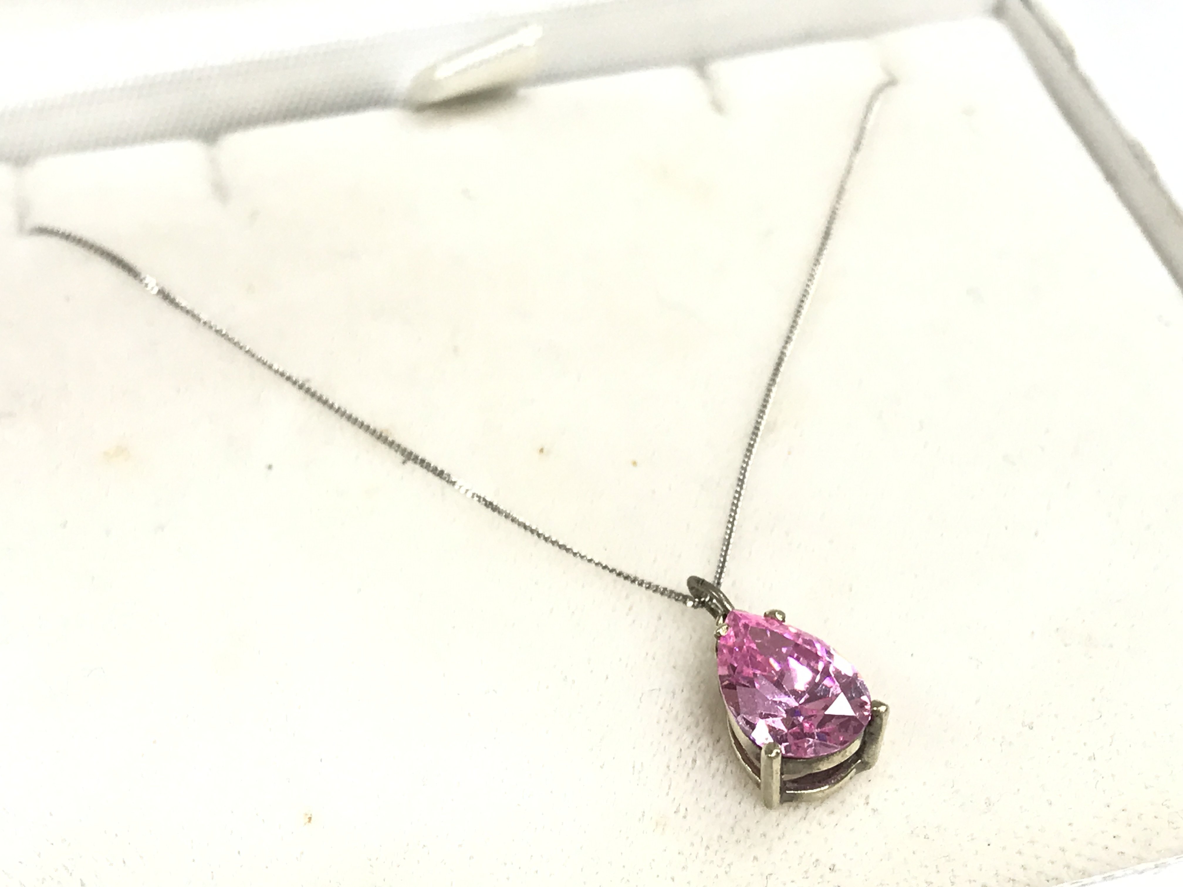A 9ct white gold chain with a pink stone pendant , 1.8g total weight. Postage category A