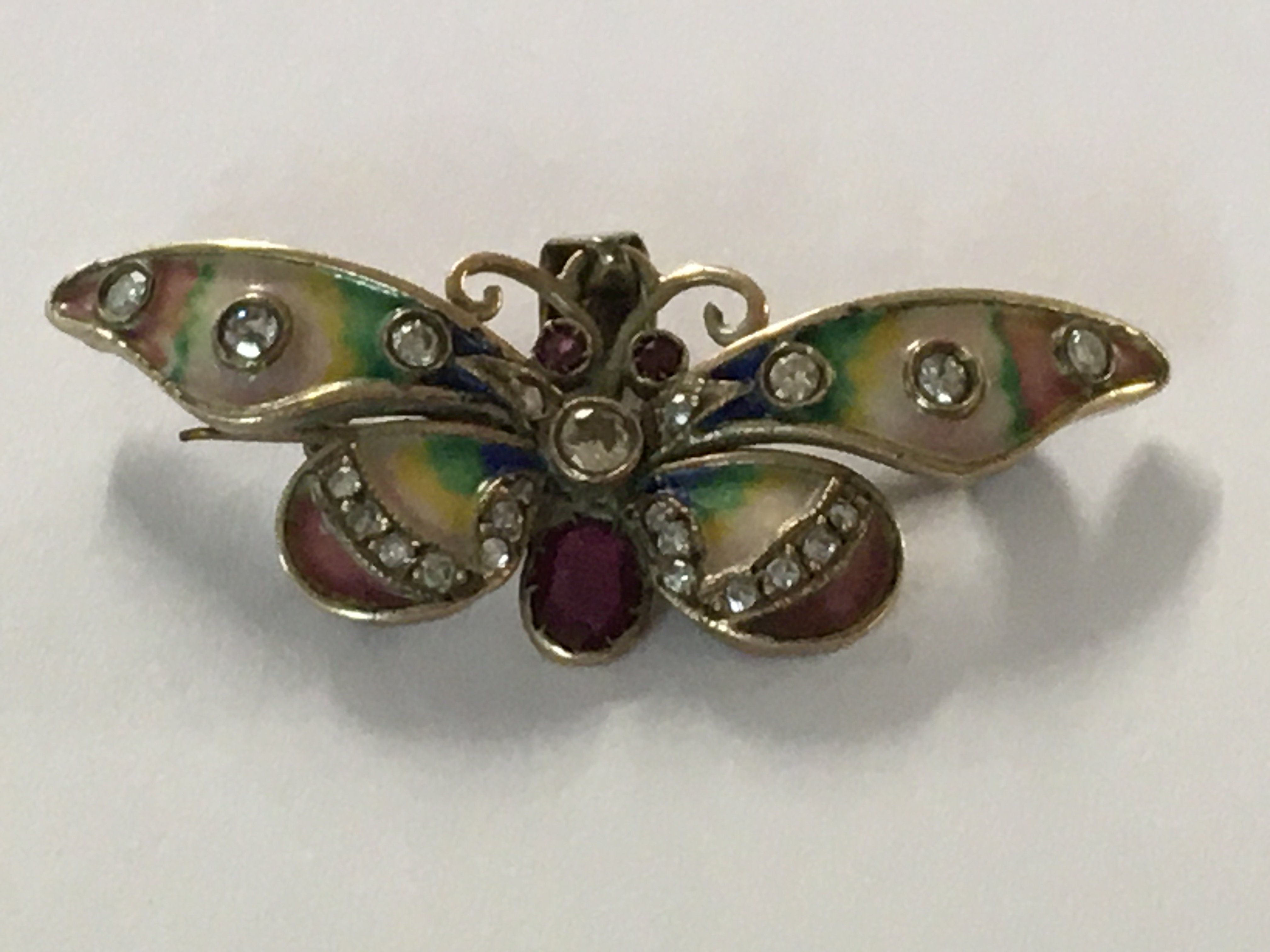 A pendant in the form of a butterfly the wings with coloured enamel inset with diamonds and rubies.