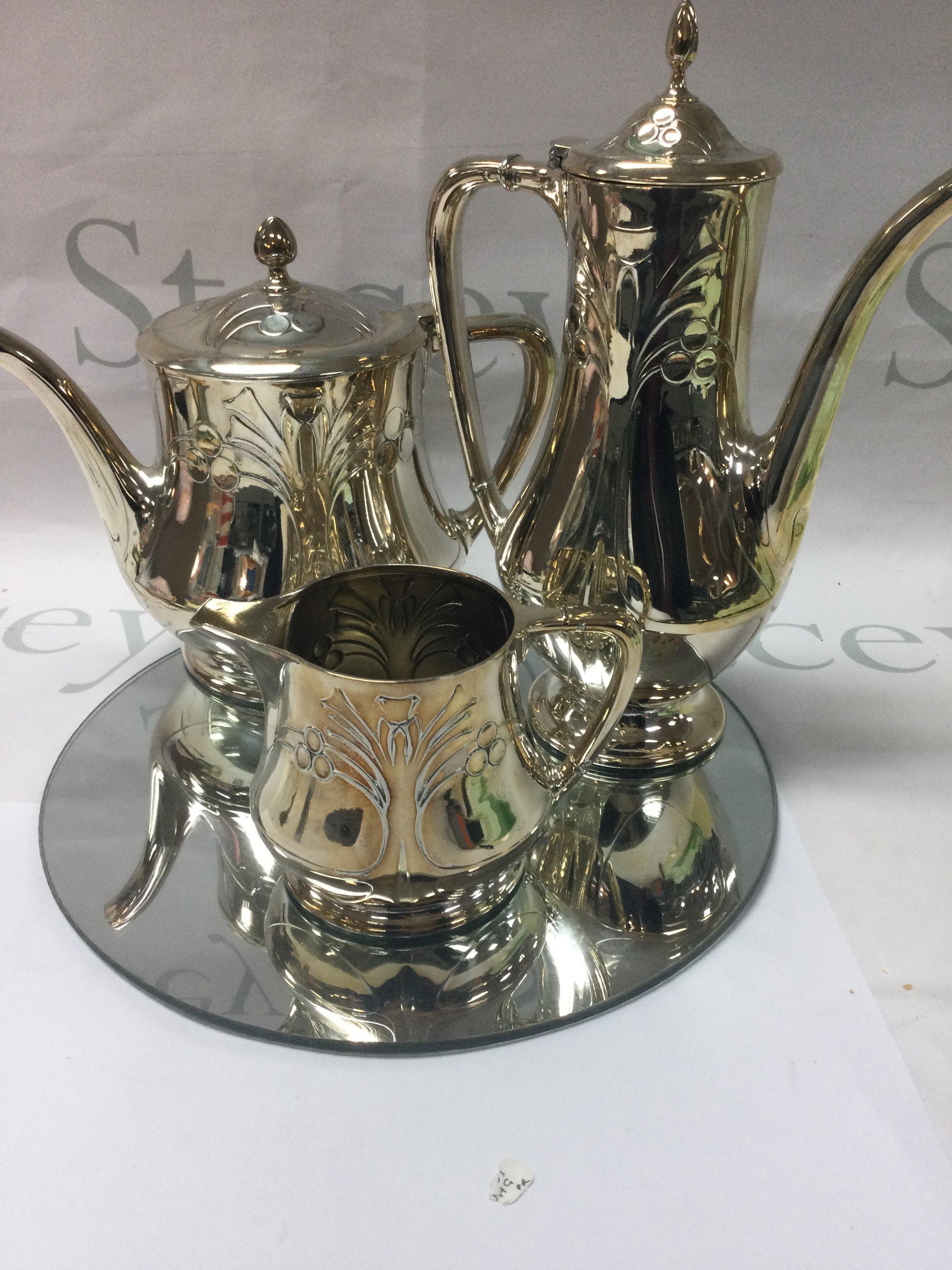 A WMF three piece tea set tea pot hot water pot milk jug having Art nouveau influence on a circle mirror base .
