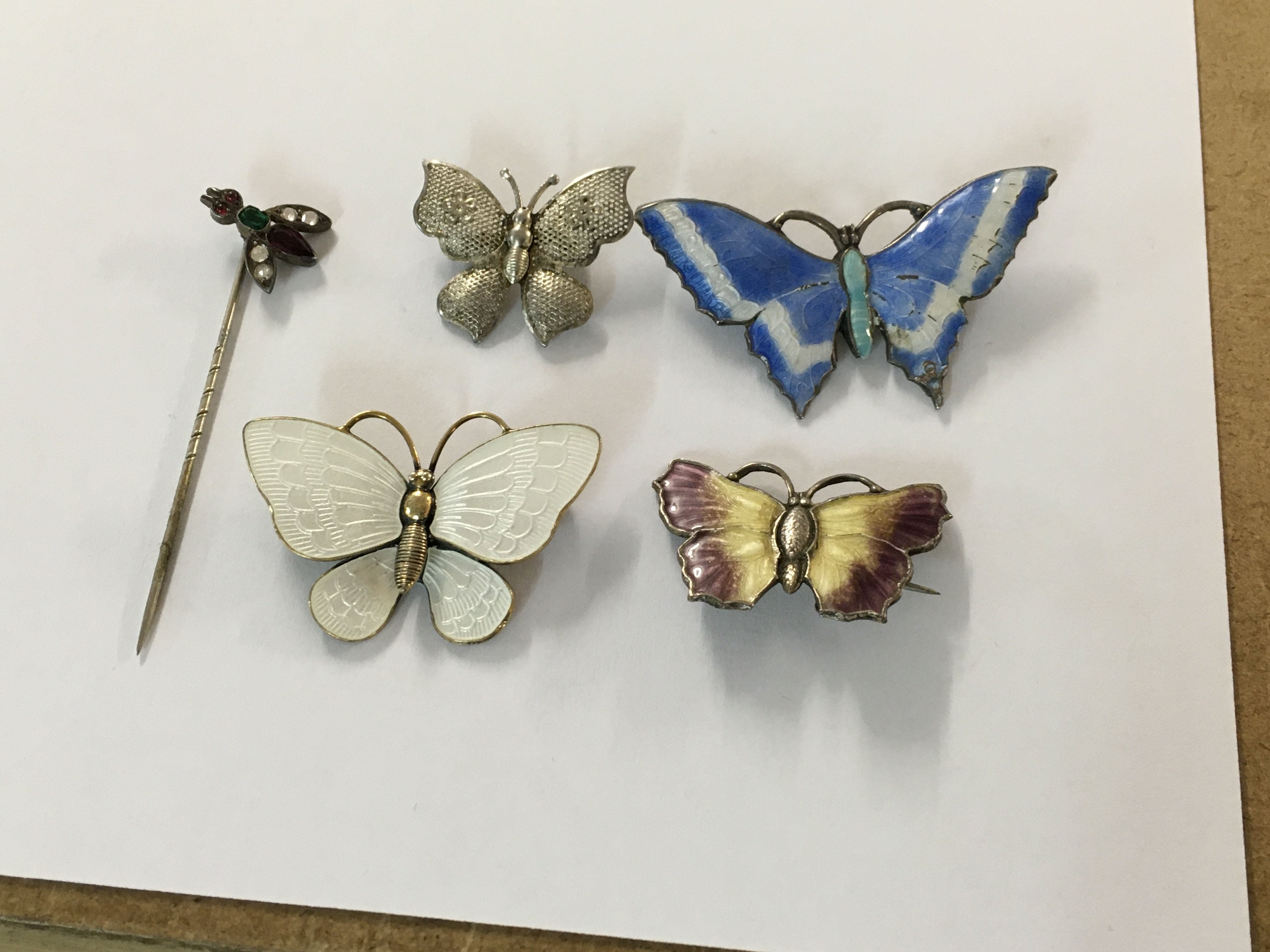 A collection of four silver and enamel brooches in the form of butterflies. And a stick pin .