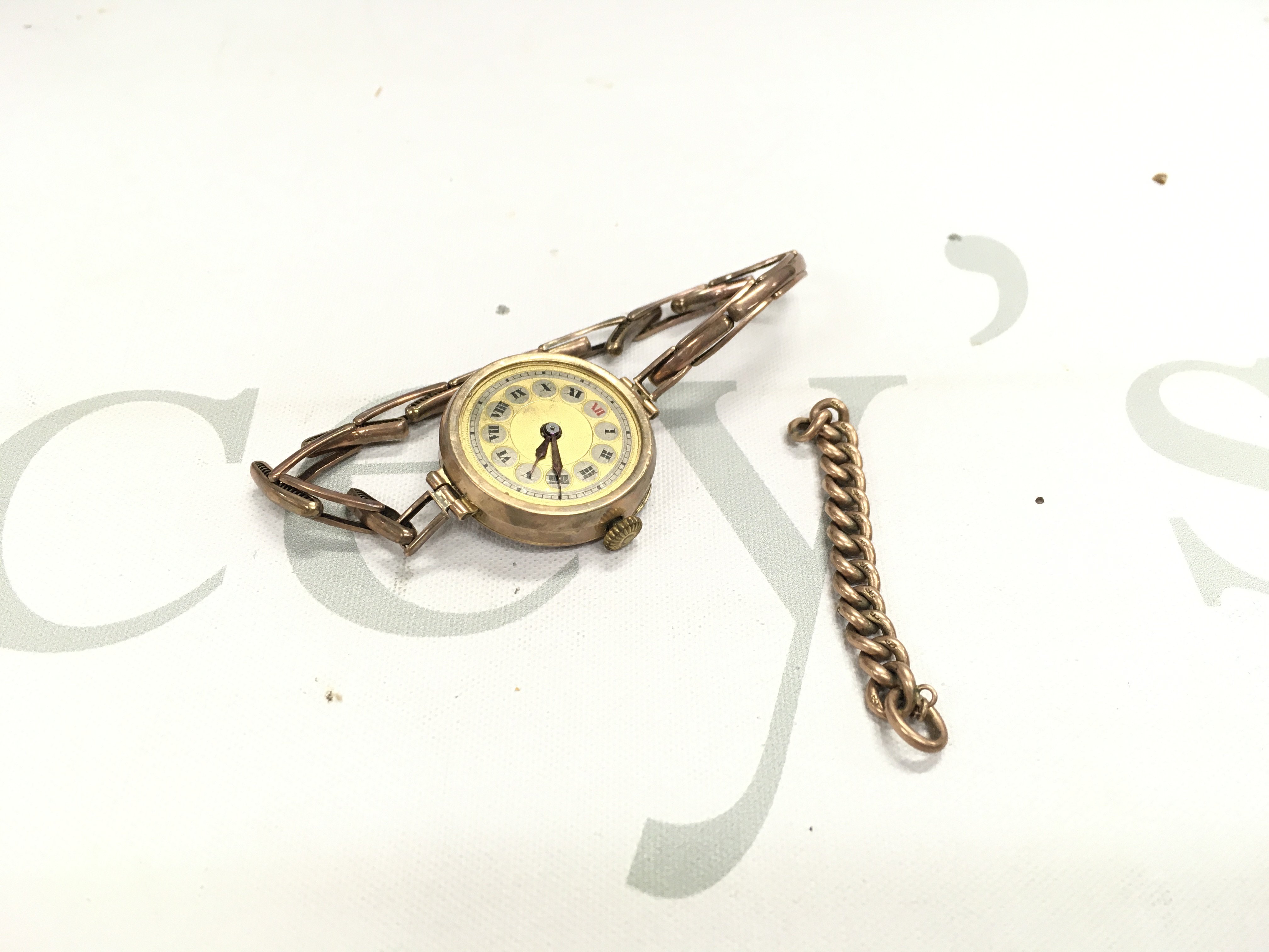 A gold cased watch and a loose piece of gold chain.