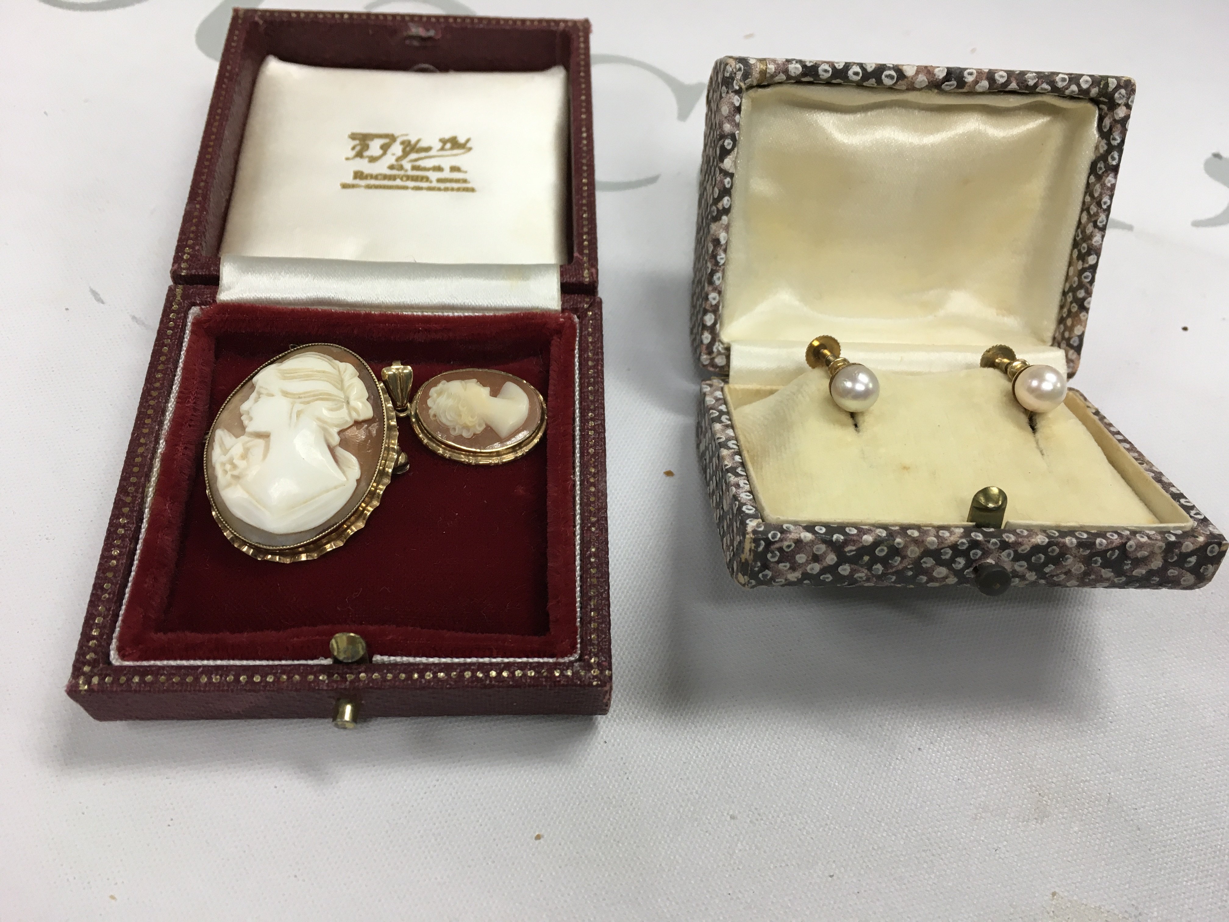 Two cameo brooches and a pair of pearl earrings.